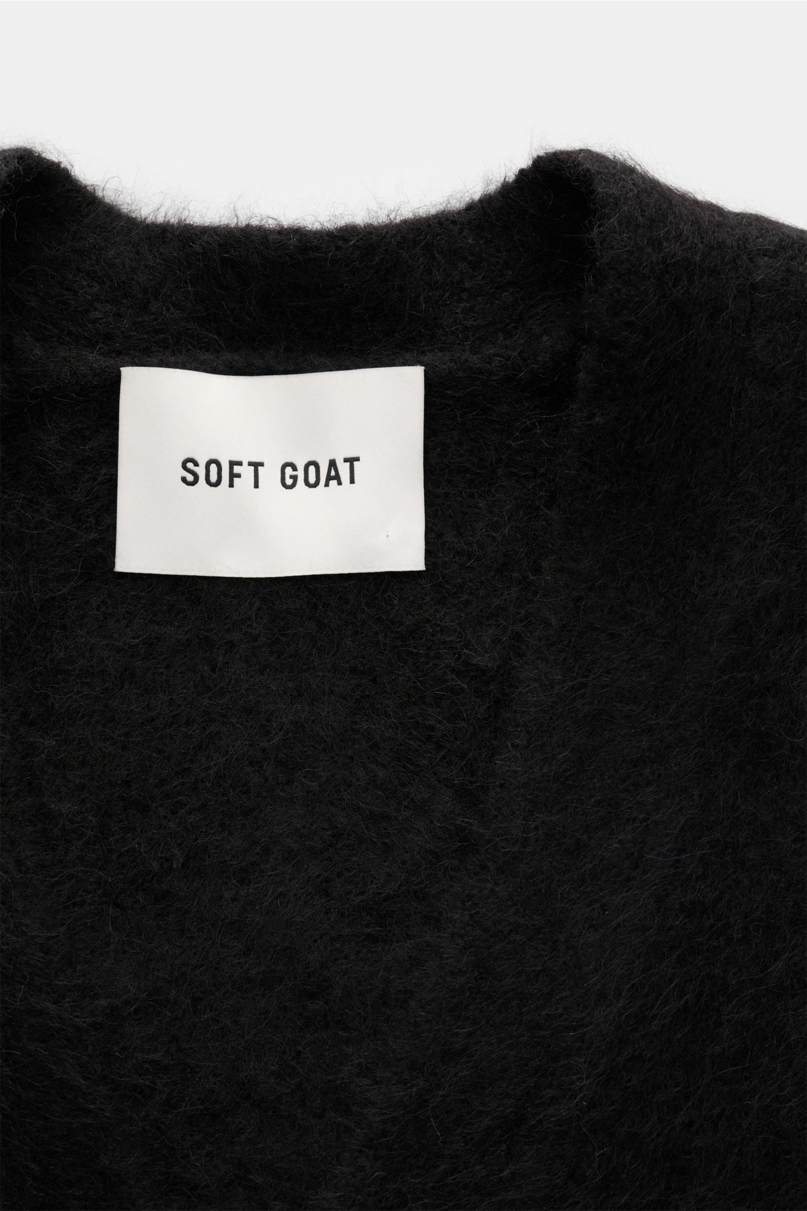 Soft Goat Cardigan schwarz, Nahaufnahme von innen auf das weiche, voluminöse Strickmaterial und das Label der nachhaltigen Alpakawolle.