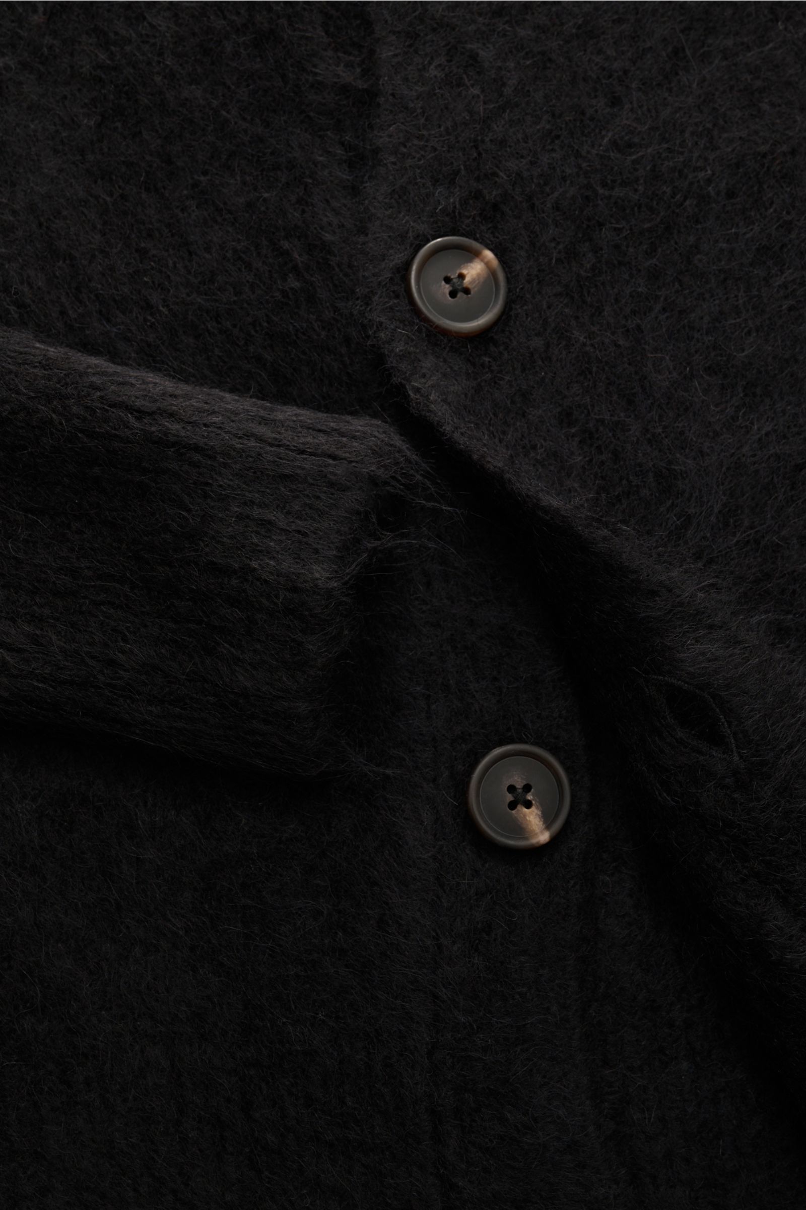 Soft Goat Cardigan schwarz in Nahaufnahme, vier Knöpfe, weiche Alpakawolle mit mittelfeinem Strickbild und breiten Rippbündchen, nachhaltig gefertigt.