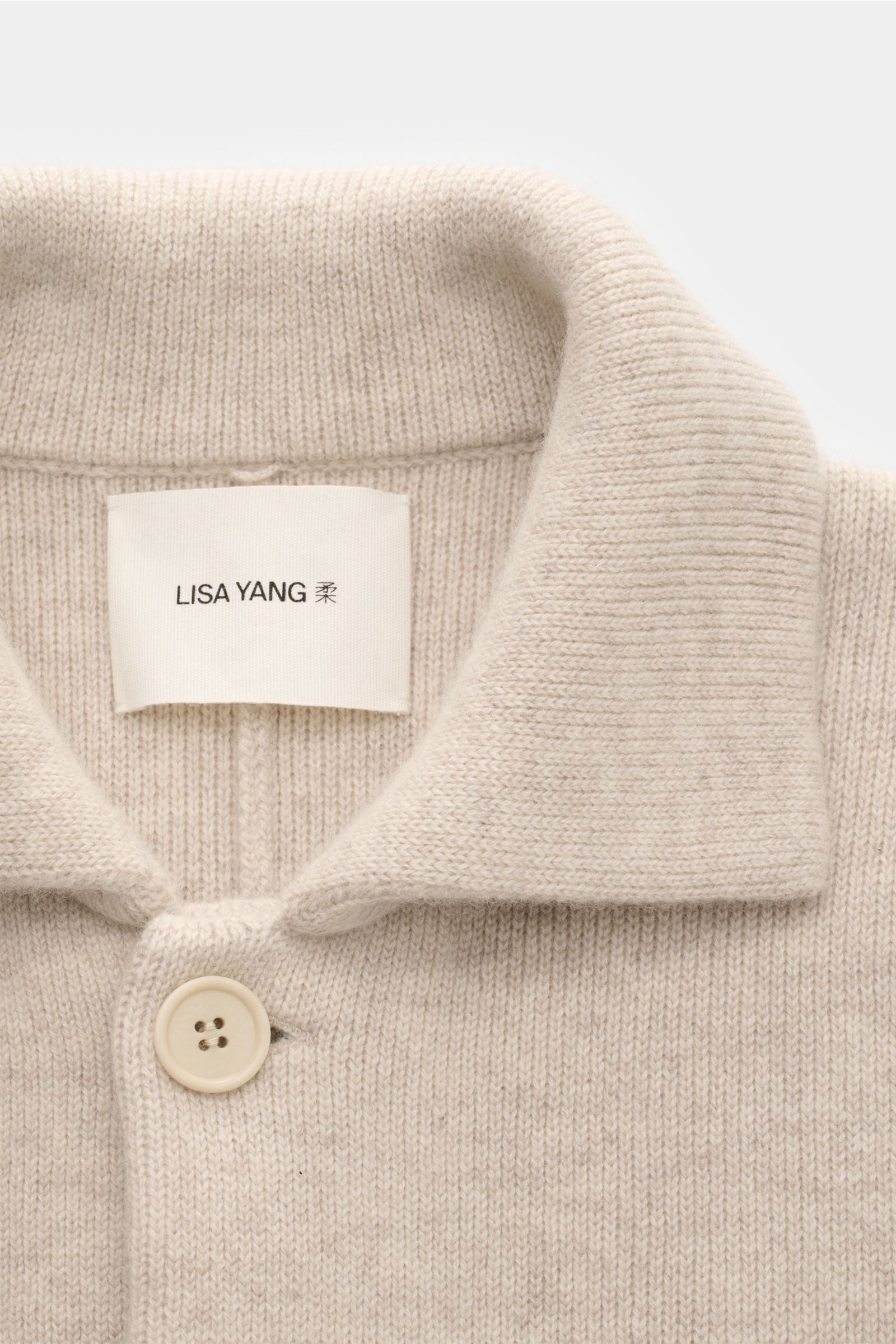 Close-up front view of the Lisa Yang Cashmere cardigan 'Louis' sand, featuring a knitted turn-down collar and single button. 

Description: Scandinavian lines by LISA YANG: The cardigan 'Louis' is made of heavy fabric in fine cashmere and is an essential 