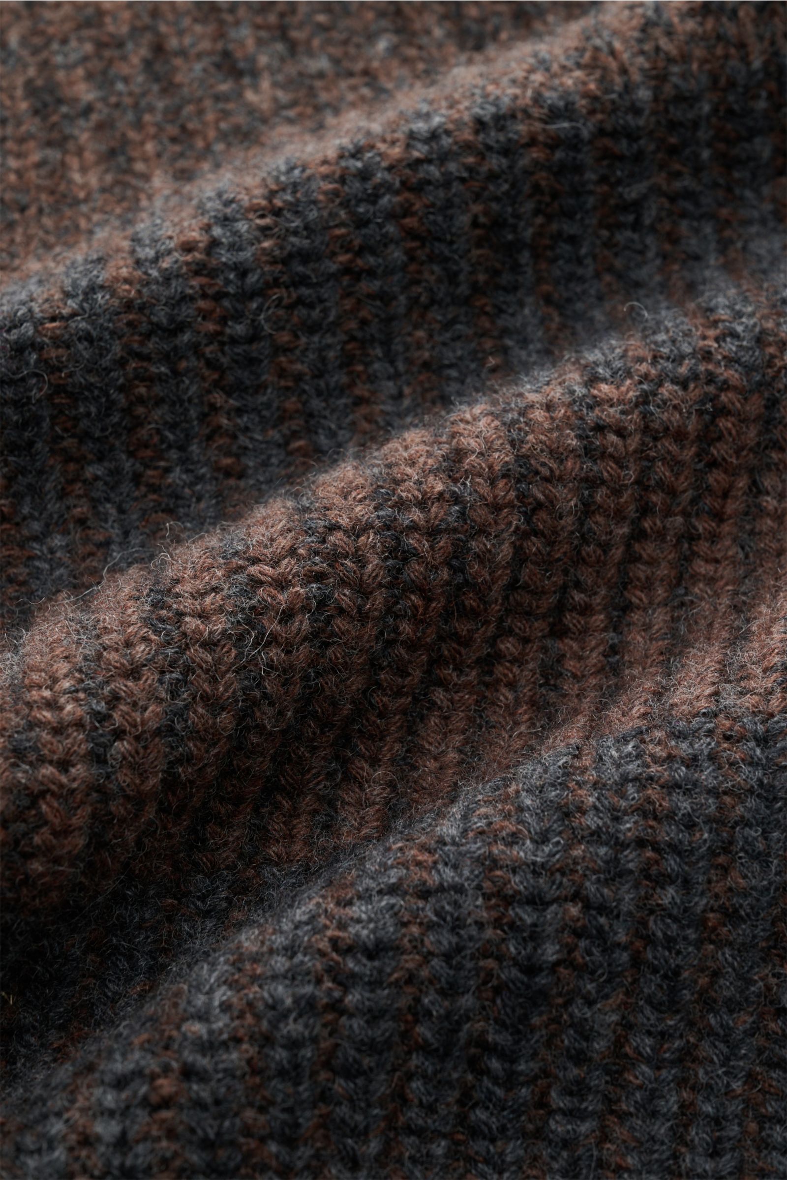 Nahaufnahme der Barbour Strickjacke 'Knit Bomber' dunkelbraun/dunkelgrau gestreift mit voluminösem, weichem Patent-Strickmuster aus reiner Wolle.