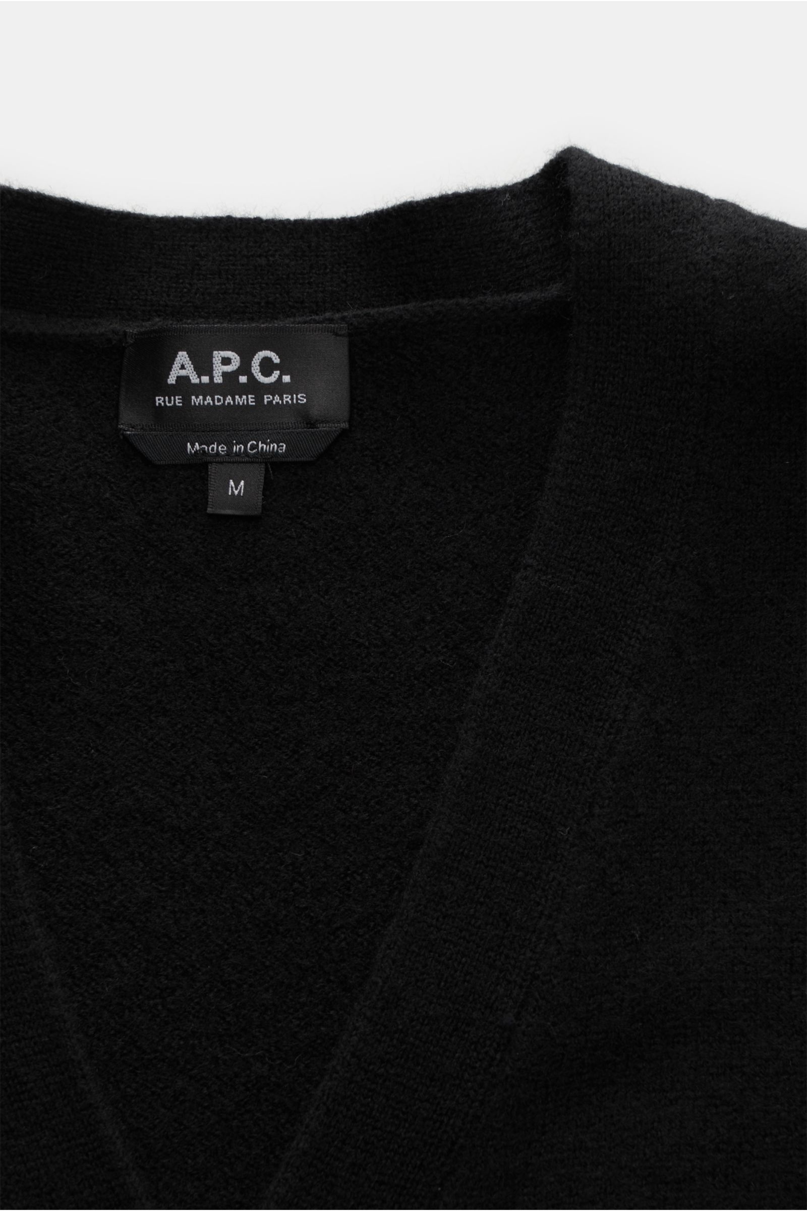 Nahaufnahme aus schräger Perspektive des schwarzen A.P.C. Cardigan 'Kenny' mit reiner Wolle, weichem Griff, mittelfeinem Strickbild, Regular Fit, Fünf-Knopf-Leiste, flexiblen Rippbündchen und dezentem Logo vorne.