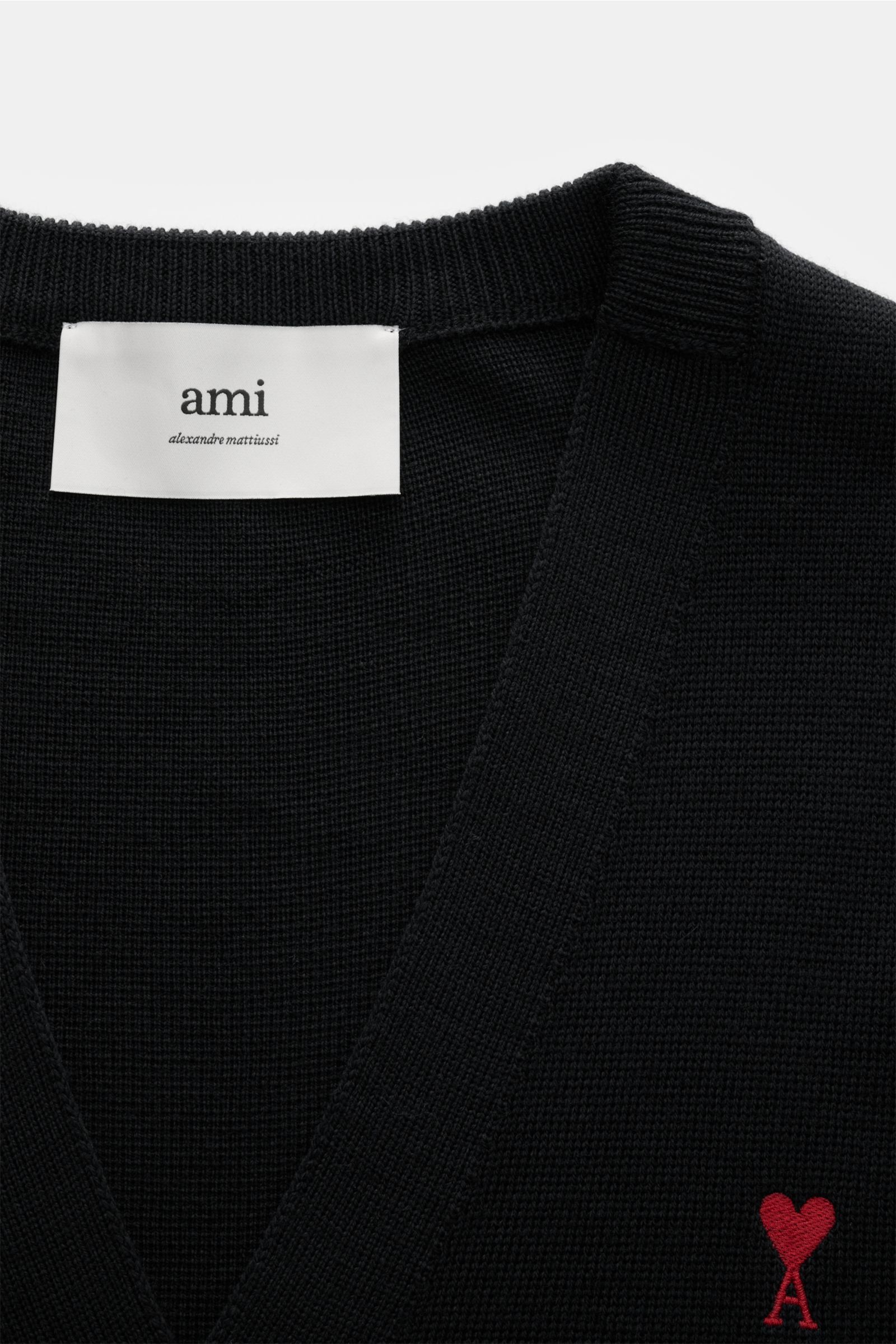 Ami Paris Merino Cardigan schwarz, Detailaufnahme von oben, minimalistischer Cardigan aus weicher Merinowolle mit V-Ausschnitt, fünf Knöpfen, elastischen Bündchen und rotem 'Ami de Cœur' Monogramm.
