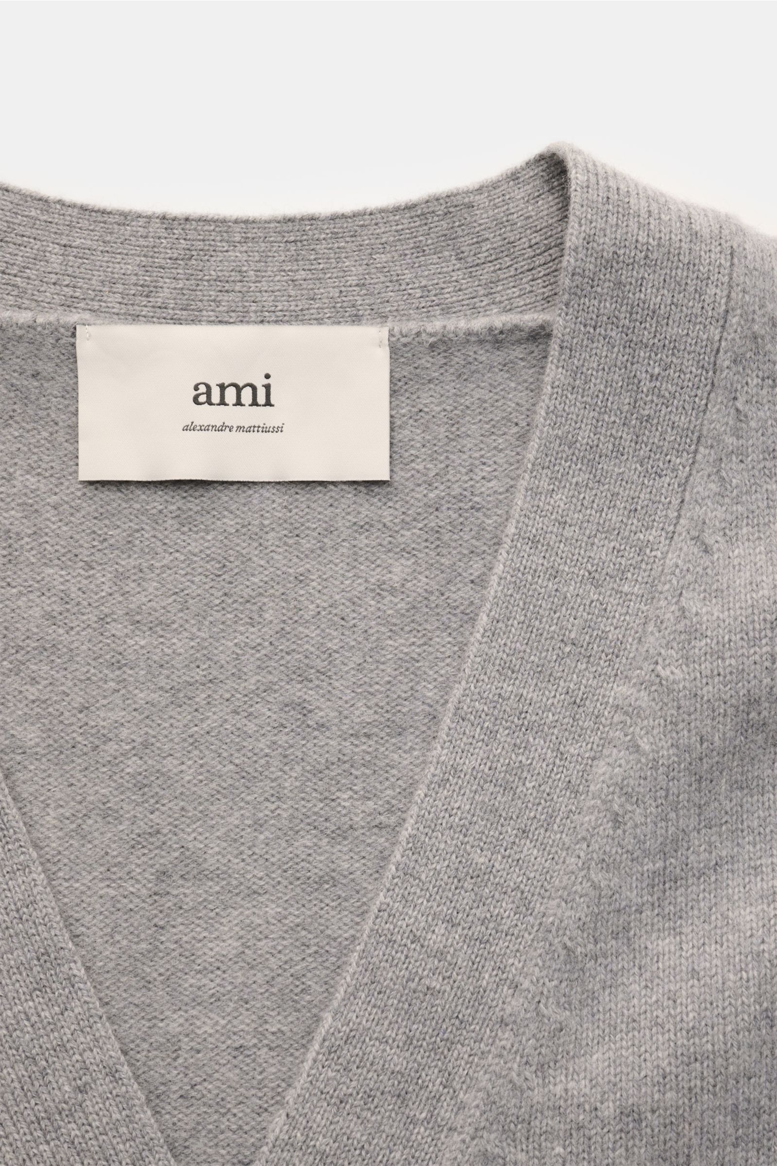 Close-up front view of the Ami Paris Cardigan grau showing soft grey wool and cashmere knit with V-neck and stitched 'Ami' logo label.

Description: Monochromes Lieblings-Piece von AMI PARIS: Der ikonische Cardigan mit typisch abgestepptem 'Ami'-Logo w