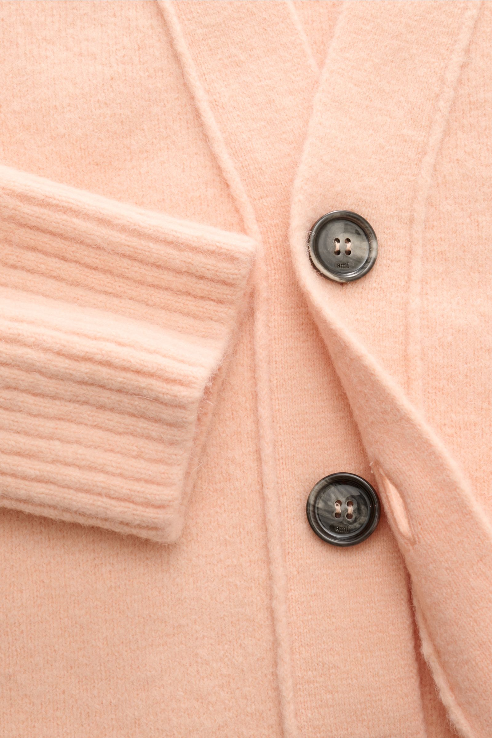 Close-up front view of the Ami Paris Cardigan rosé showing soft alpaca blend fabric, ribbed cuff, five-button placket with logo-engraved buttons. Legerer Luxus für kalte Tage: AMI PARIS interpretiert seinen ikonischen Cardigan mit großem Herz-Logo in eine