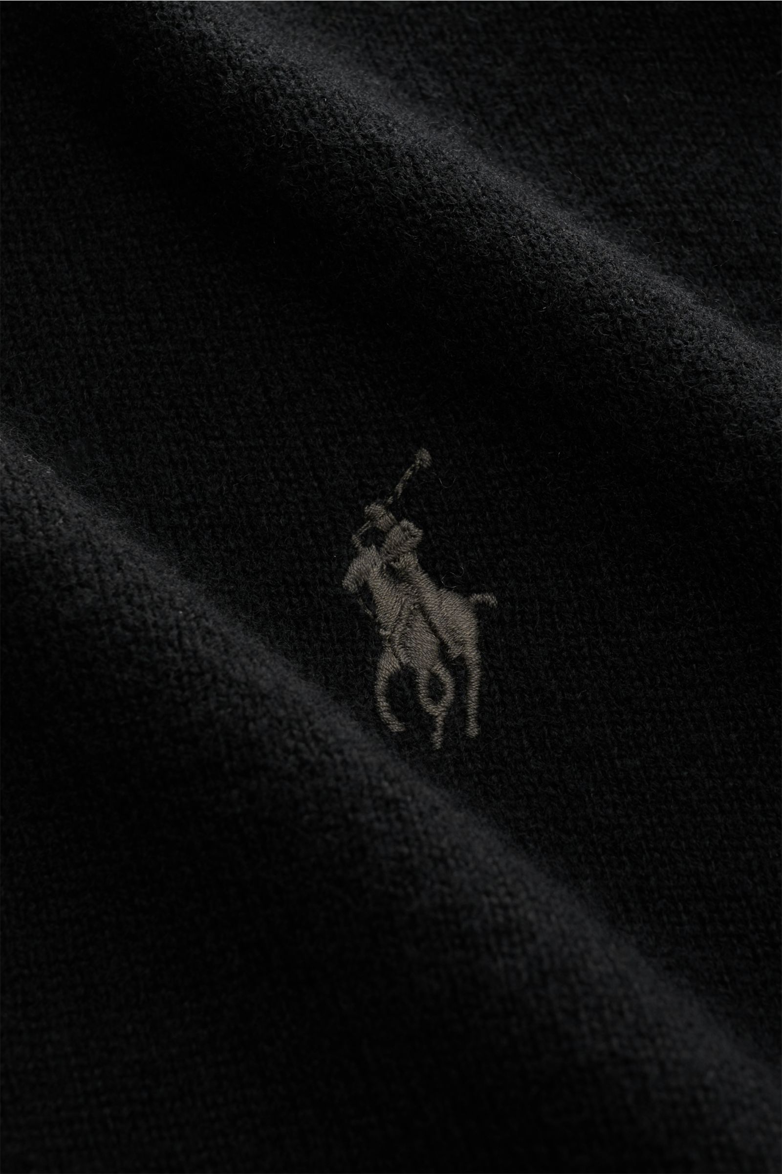 Polo Ralph Lauren Strickjacke schwarz aus reiner, weicher Wolle mit feinem Strickbild, hoch schließendem Stehkragen und Logo, Nahaufnahme.