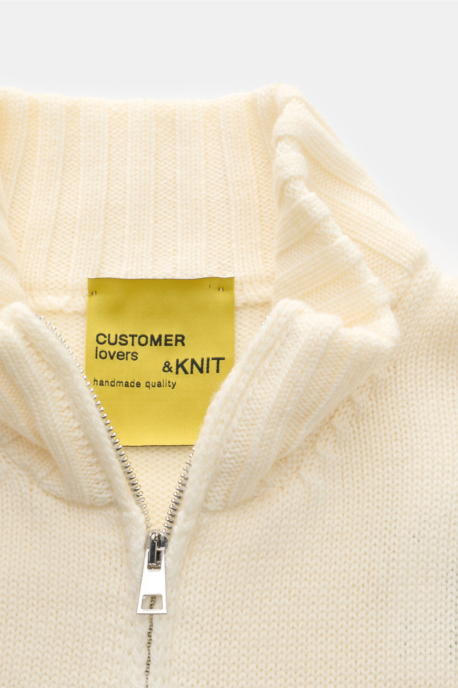 Nahaufnahme der B.F. Knitwear Merino Strickjacke creme mit hochschließendem Stehkragen, Zwei-Wege-Reißverschluss und mittelgrobem Strickbild.