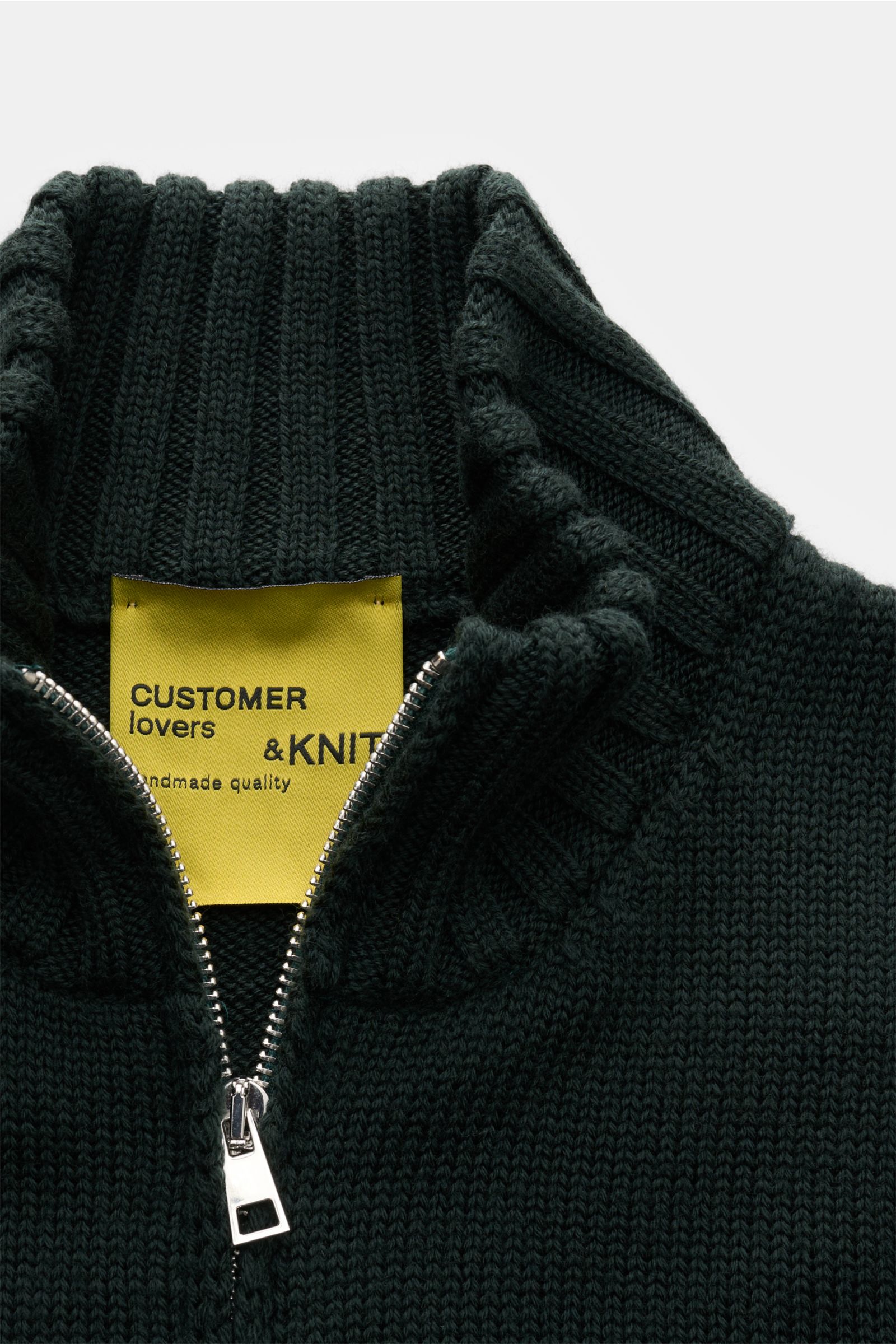 B.F. Knitwear Merino Strickjacke dunkelgrün aus reiner Merinowolle, slim fit, mittelgrobes Strickbild, Stehkragen mit Zwei-Wege-Reißverschluss, Detailfoto von oben.