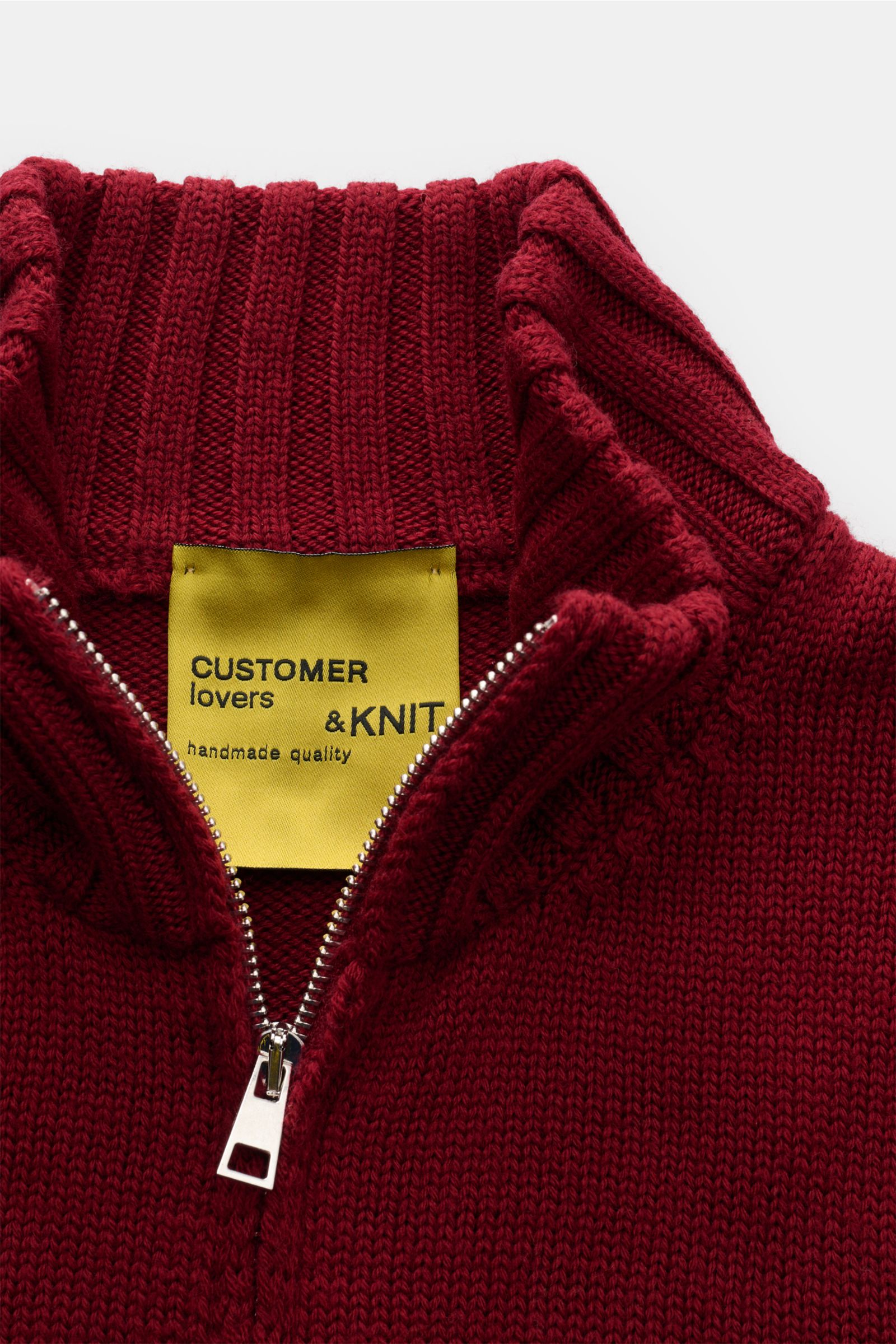 Close-up front view of the B.F. Knitwear Merino Strickjacke dunkelrot in dark red, showing the smooth Merino wool knit, slim fit, two-way zipper, high stand collar, round neckline, and ribbed cuffs. Hochwertiger Allrounder für kühle Tage: Die Strickjac
