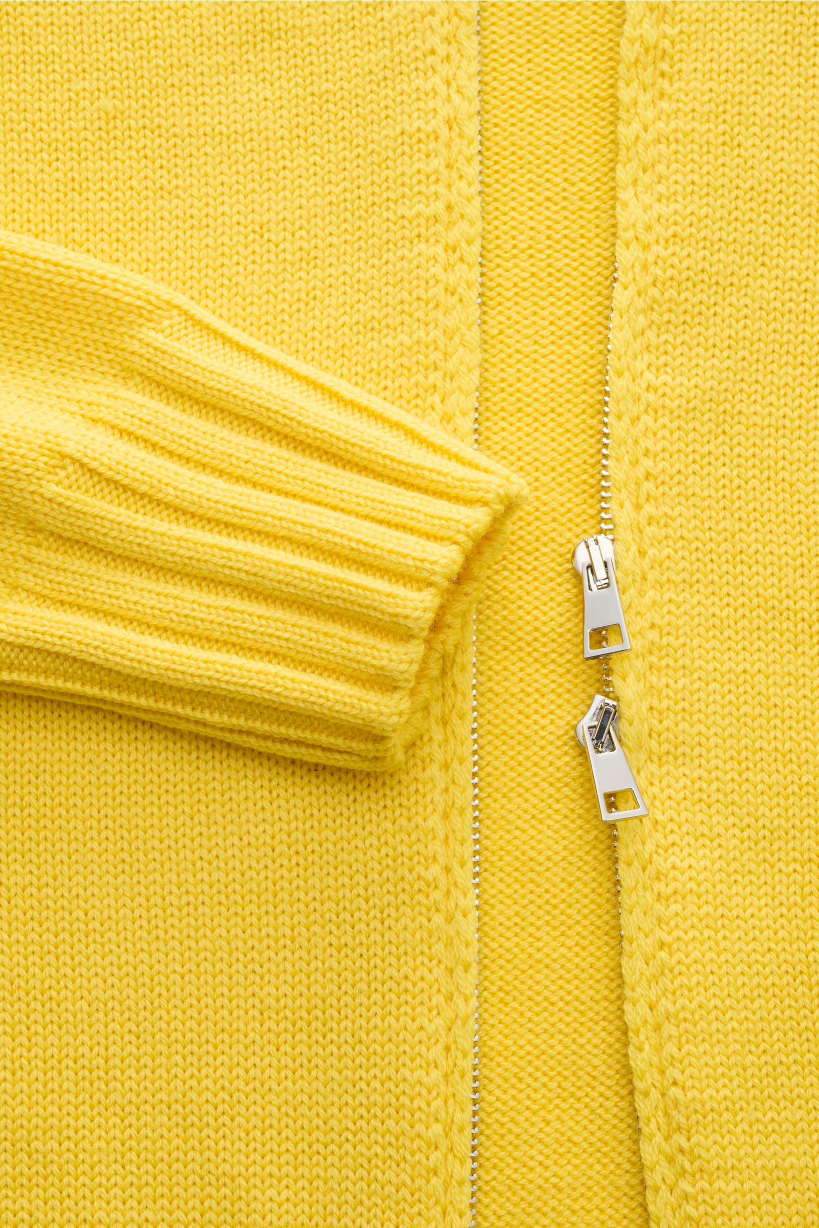 Nahaufnahme der B.F. Knitwear Merino Strickjacke gelb aus reiner Merinowolle, Slim Fit, mit zwei-Wege-Reißverschluss, Stehkragen und Rippbündchen.