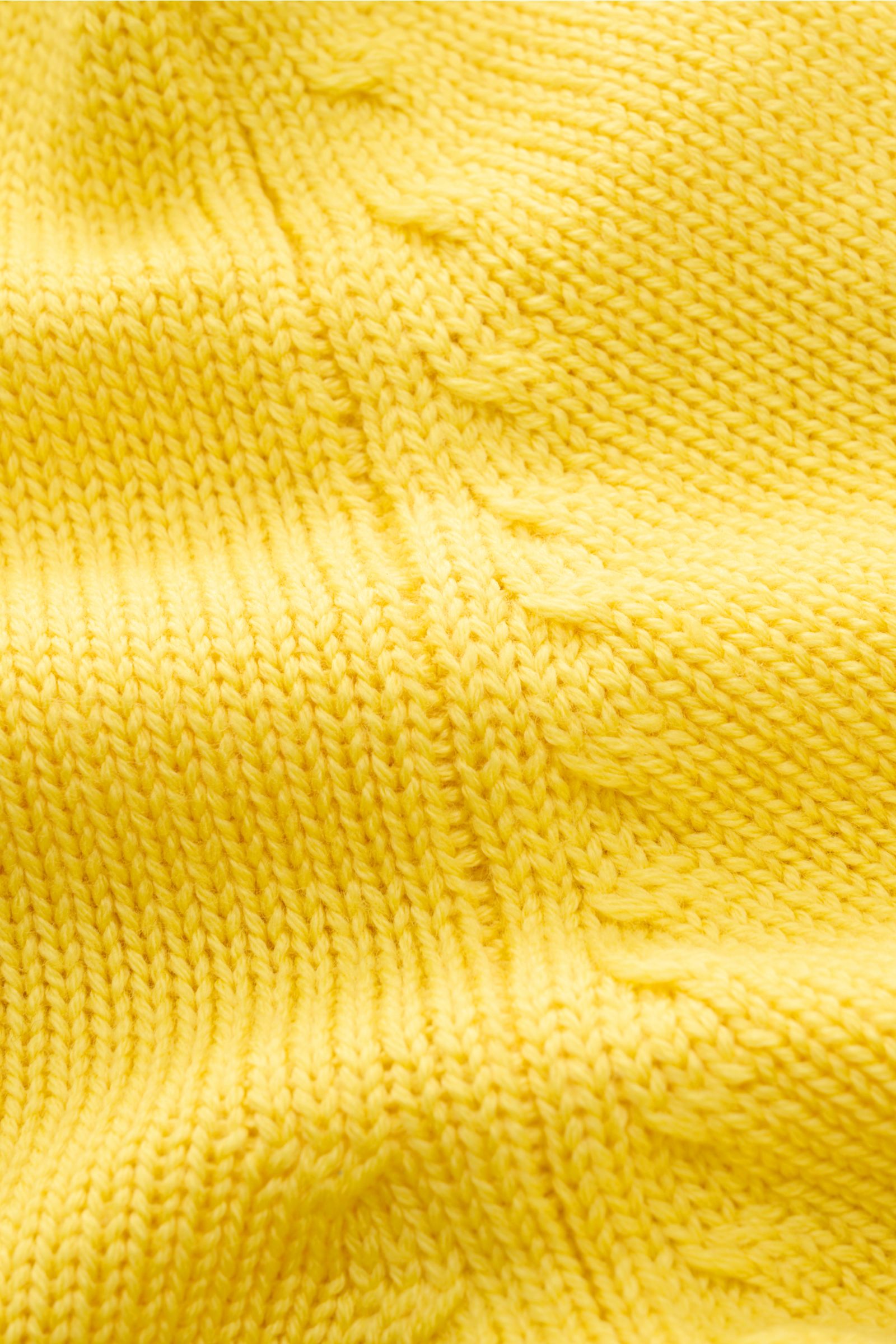 Nahaufnahme der gelben B.F. Knitwear Merino Strickjacke gelb mit mittelgrobem Strickbild aus reiner Merinowolle, weichem Griff und Zopfmuster.