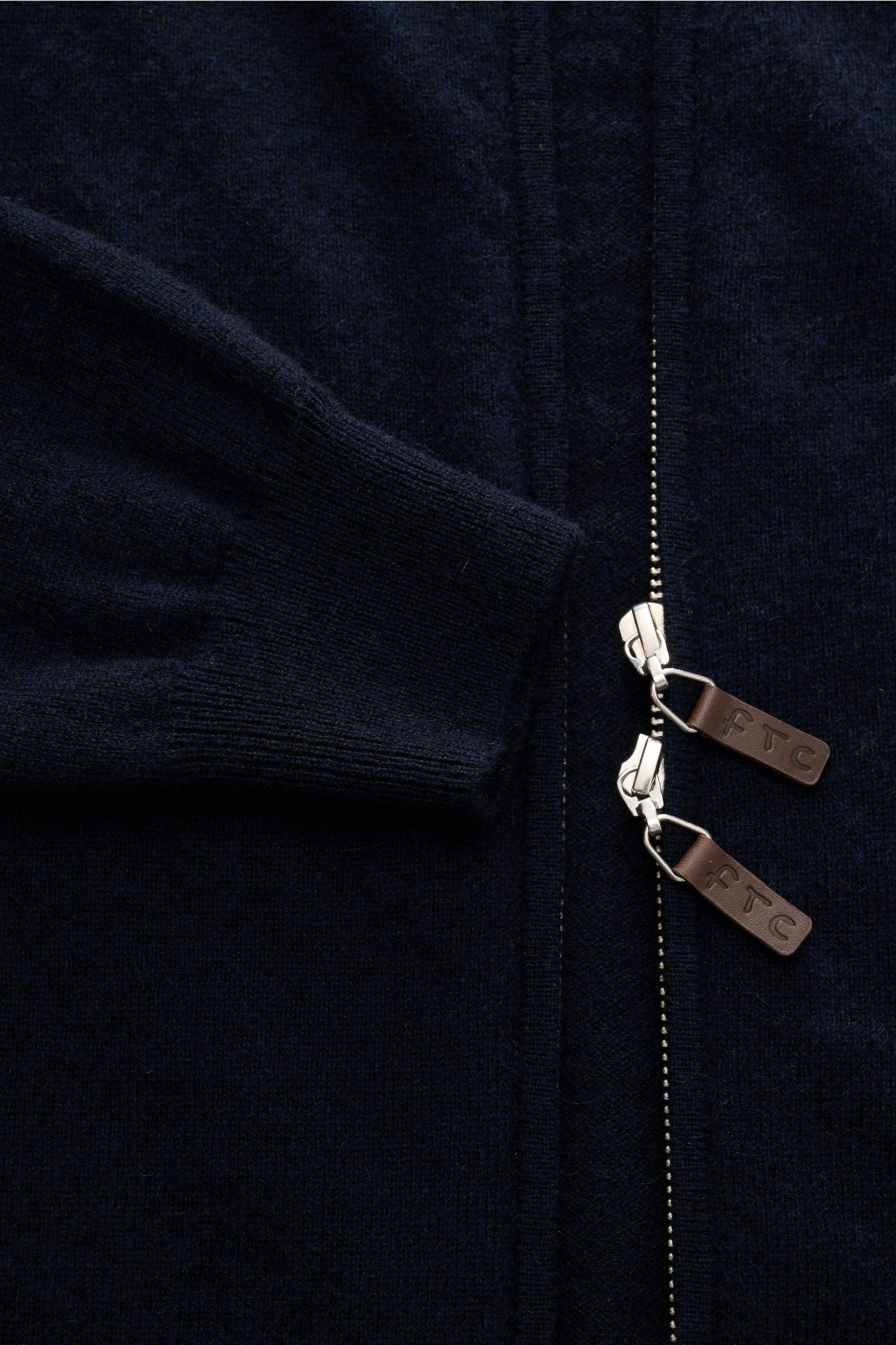 Nahaufnahme der FTC Cashmere Strickjacke navy von vorne, zeigt feines Strickbild, Slim Fit, gerippten Stehkragen, Reißverschluss mit Leder-Logo und flexible Rippbündchen, Fair-Trade-Cashmere, OEKO-TEX® Standard 100 zertifiziert.