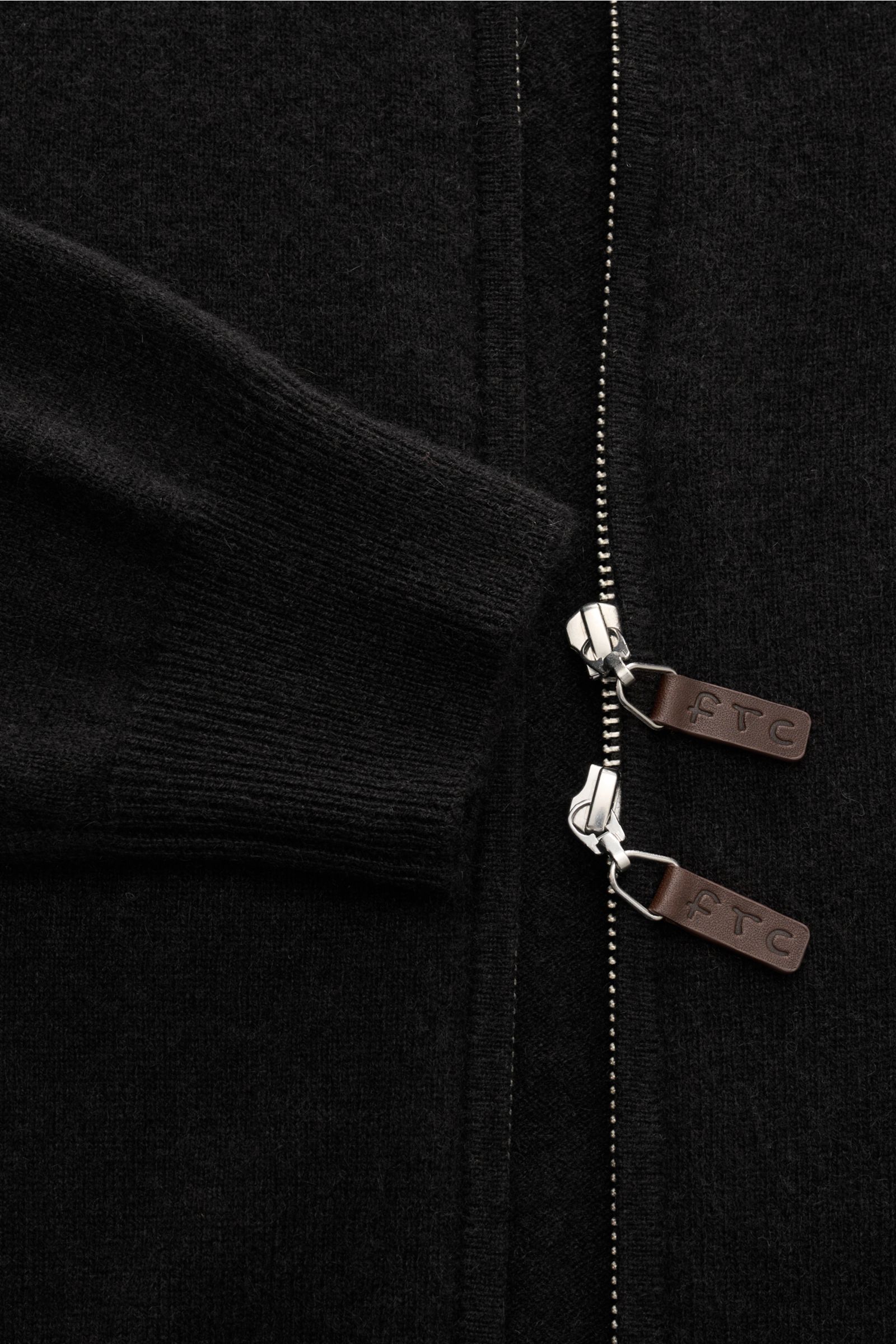 Nahaufnahme der dunkelbraunen FTC Cashmere Strickjacke aus Fair-Trade-Cashmere mit feinem Strickbild, Slim Fit, verdecktem Zwei-Wege-Reißverschluss und ledernen Zipper-Details, fotografiert von oben.