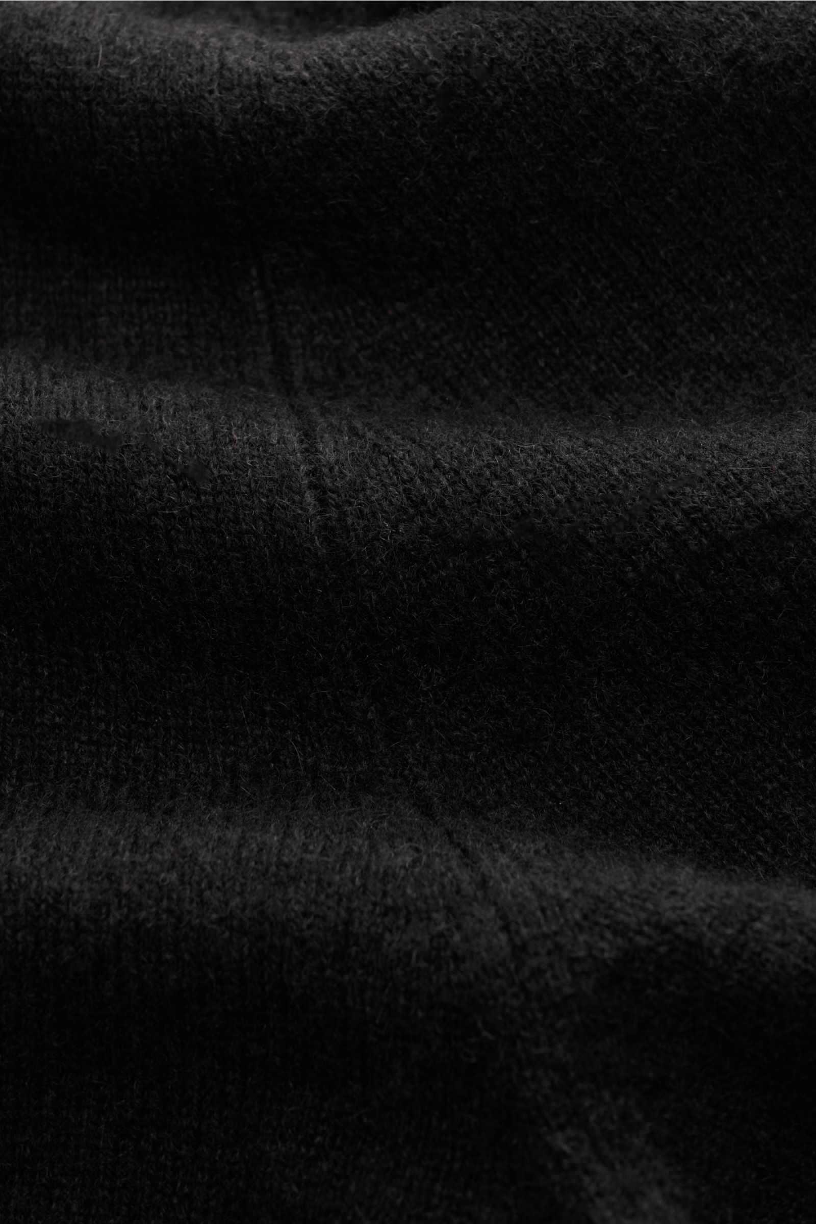 Das Bild zeigt eine Nahaufnahme der fein gestrickten Oberfläche der FTC Cashmere Strickjacke dunkelbraun, die aus reiner Fair-Trade-Cashmere gefertigt ist. Das Foto hebt den sehr weichen Griff, das feine Strickbild und die nachhaltige Produktion hervor. D