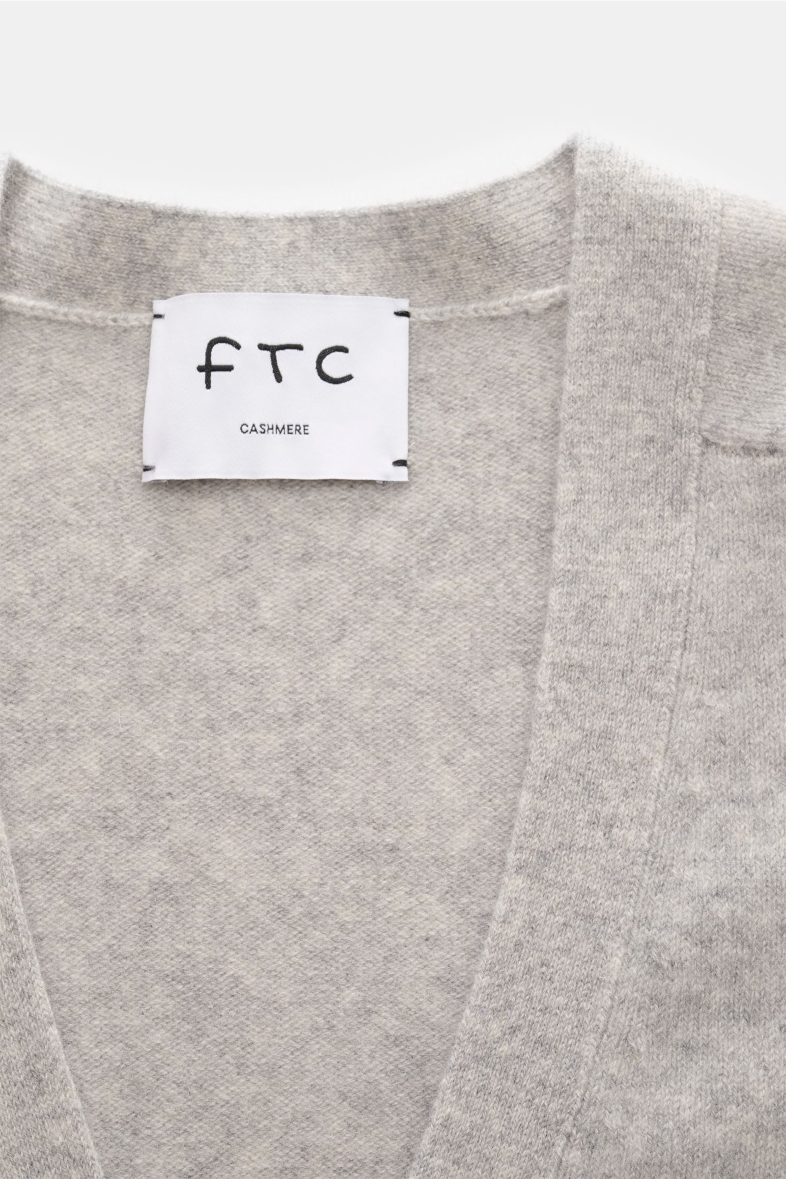 Nahaufnahme des FTC Cashmere Cardigan grau meliert von oben, zeigt V-Ausschnitt, weichen, mittelfeinen Fair-Trade-Cashmere-Strick, elastische Qualität.