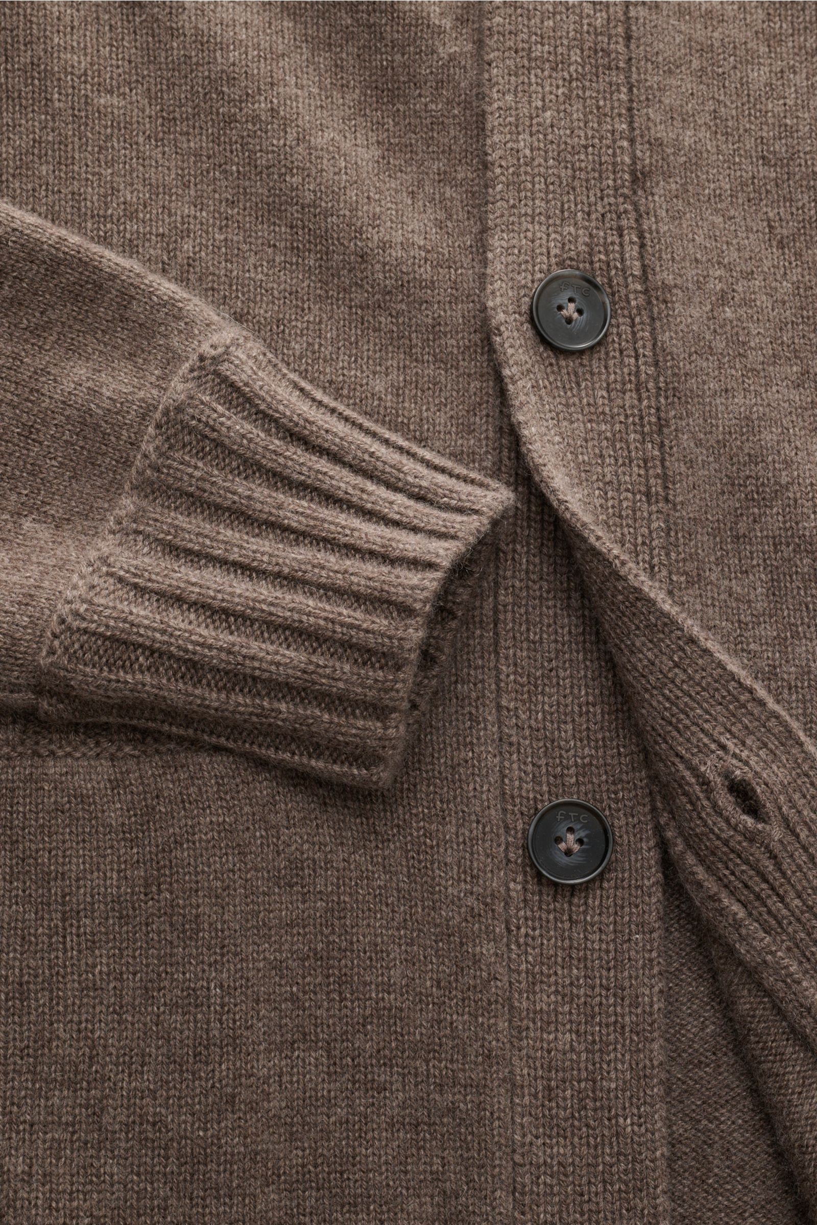 Nahaufnahme des graubraunen FTC Cashmere Cardigan aus reinem Fair-Trade-Cashmere, mittelfeines Strickbild, Slim Fit, V-Ausschnitt, Vier-Knopf-Leiste, Halbraglan-Ärmel, Leistentaschen und komfortable Rippbündchen, fotografiert von oben.