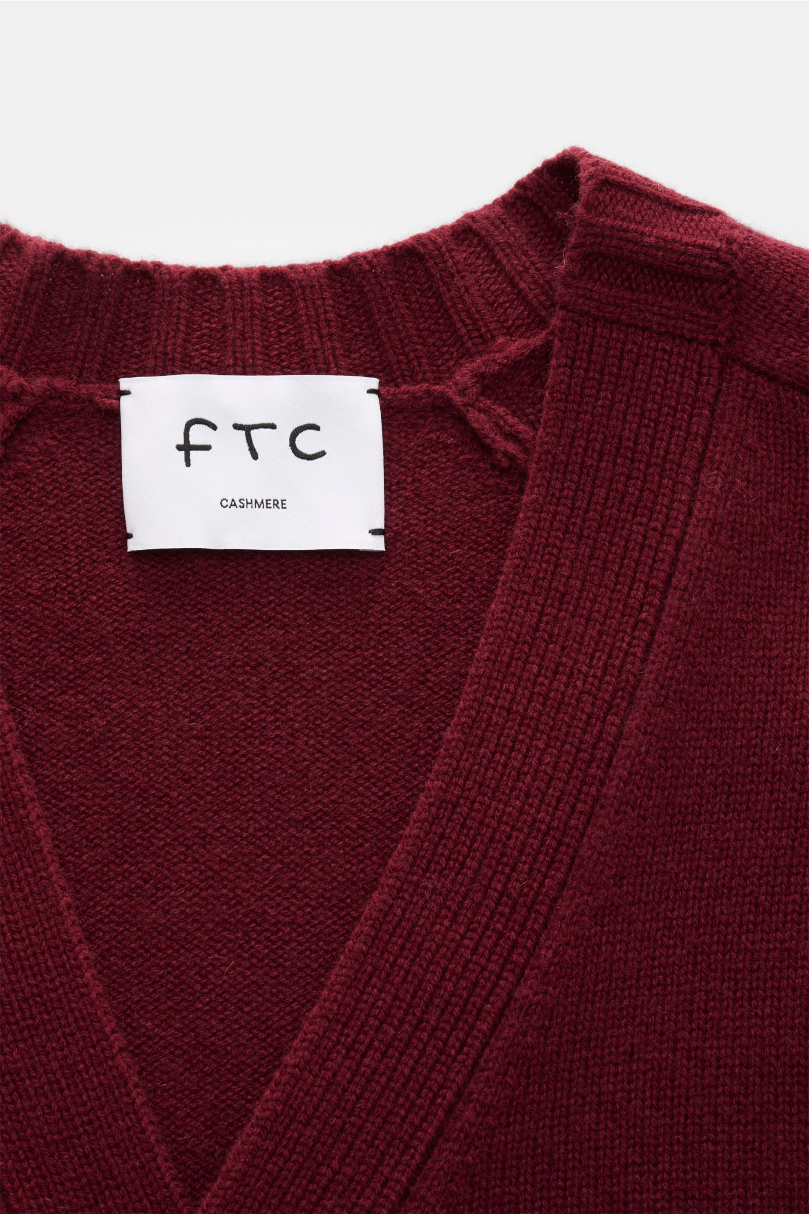 Nahaufnahme des FTC Cashmere Cardigan bordeaux von oben, zeigt V-Ausschnitt, mittelfeines Strickbild und weiches Fair-Trade-Cashmere.