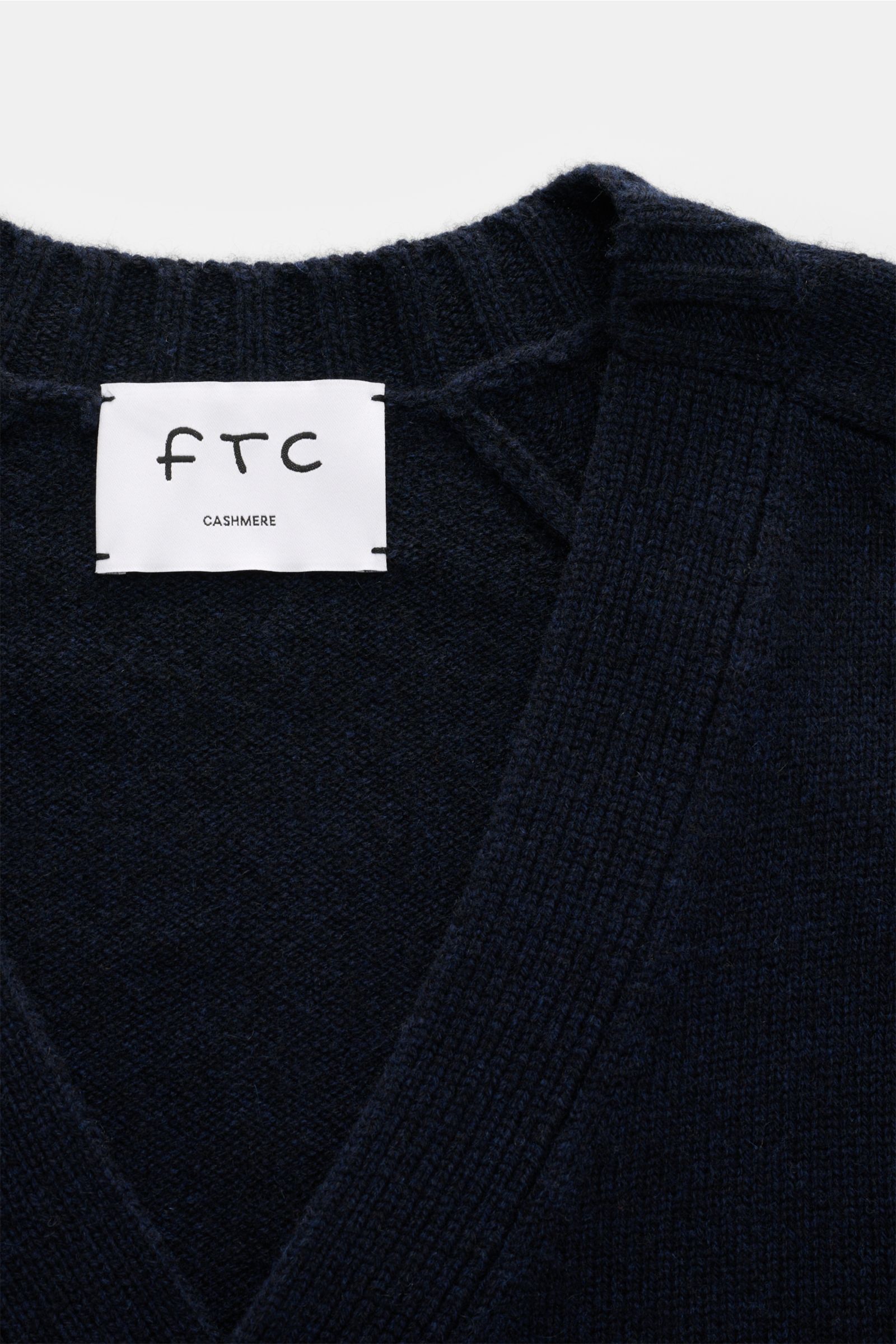 Nahaufnahme des FTC Cashmere Cardigan navy von oben mit V-Ausschnitt, weichem, mittelfeinem Fair-Trade-Cashmere-Strick und Label.