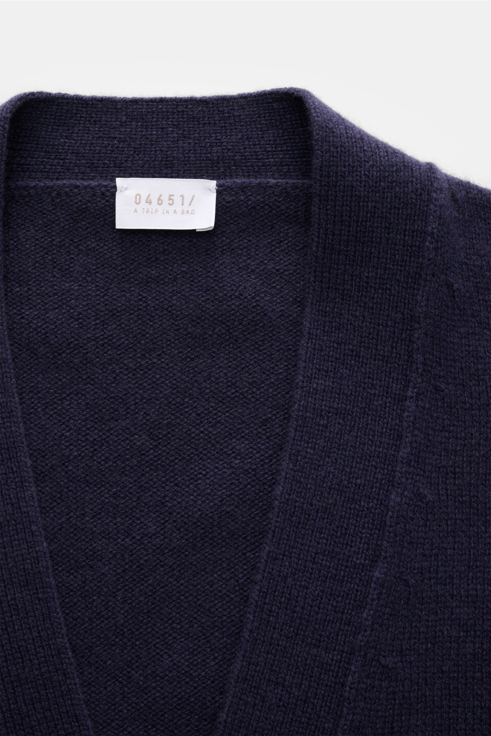 Close-up front view of the 04651/ A trip in a bag Cardigan navy, showing fine knit wool-cashmere fabric and ribbed collar. Subtle luxury: Fine material in wool and cashmere and the contrasting pocket make this cardigan by 04651/ A TRIP IN A BAG an eye-cat