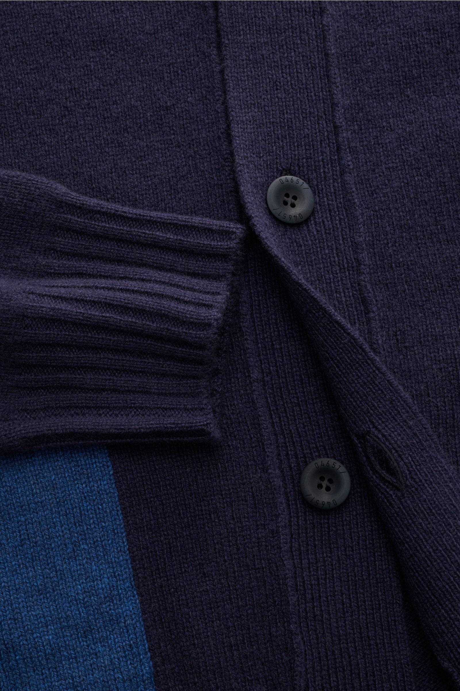 Close-up top-down view of the 04651/ A trip in a bag Cardigan navy, showcasing fine knit wool and cashmere material with a soft feel, ribbed cuff, four-button placket, and a contrasting blue hip pocket. Subtle luxury: Fine material in wool and cashmere an