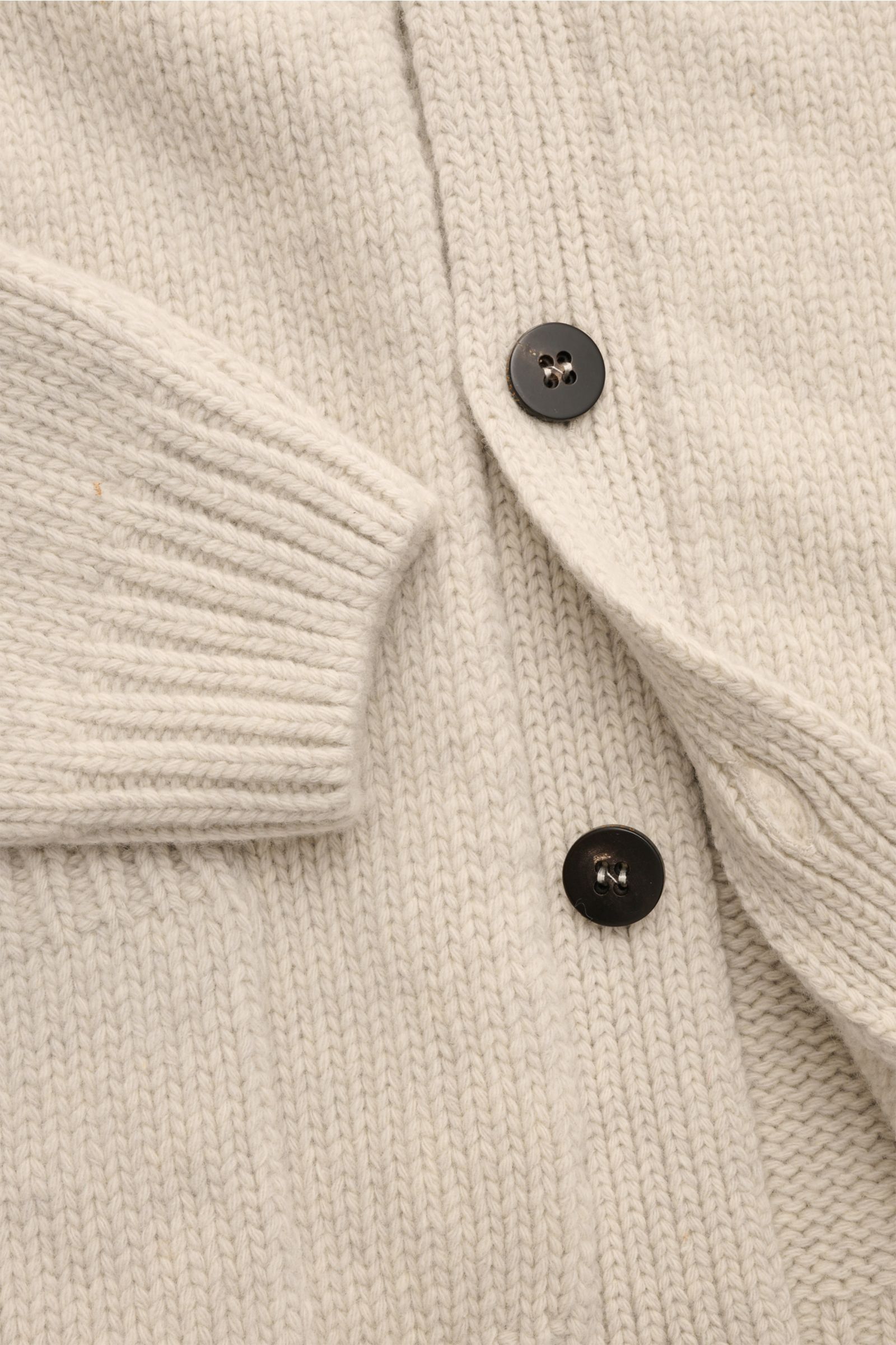 Nahaufnahme des 04651/ A trip in a bag Cardigan 'Bold' hellgrau meliert mit grobem Strickbild, Vier-Knopf-Leiste und aufgesetzter Fronttasche.