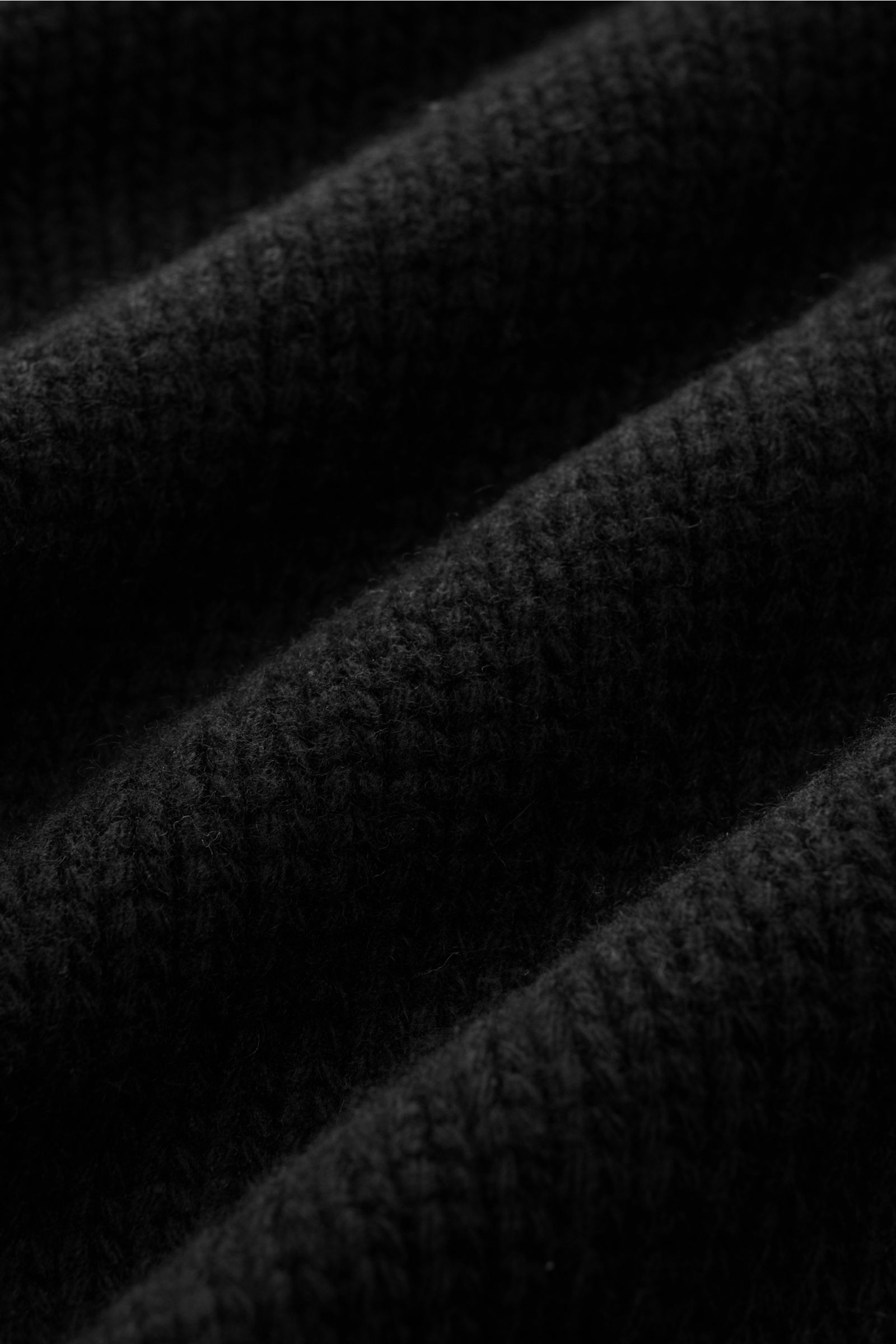 Close-up des grob gestrickten, schwarzen 04651/ A trip in a bag Cardigan 'Bold' aus reiner Lammwolle mit weichem Griff.