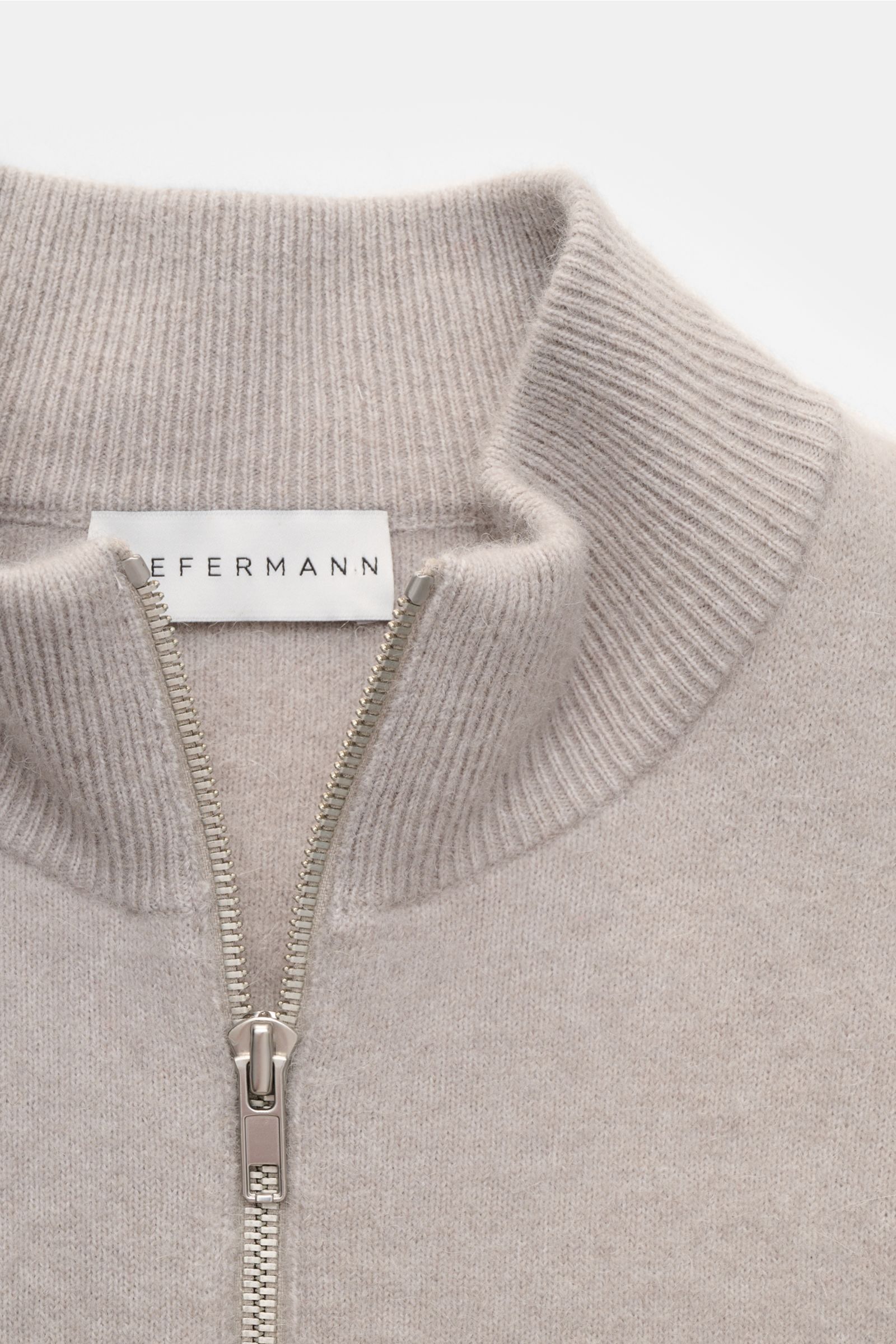 Close-up front view of the Kiefermann Strickjacke 'Fabions' hellgrau meliert, a light gray melange cardigan with a ribbed collar, silver zipper, and fine knit texture. Luxuriöses Basic für die kalte Jahreszeit: Die Strickjacke im Blouson-Stil von KIEFERMA