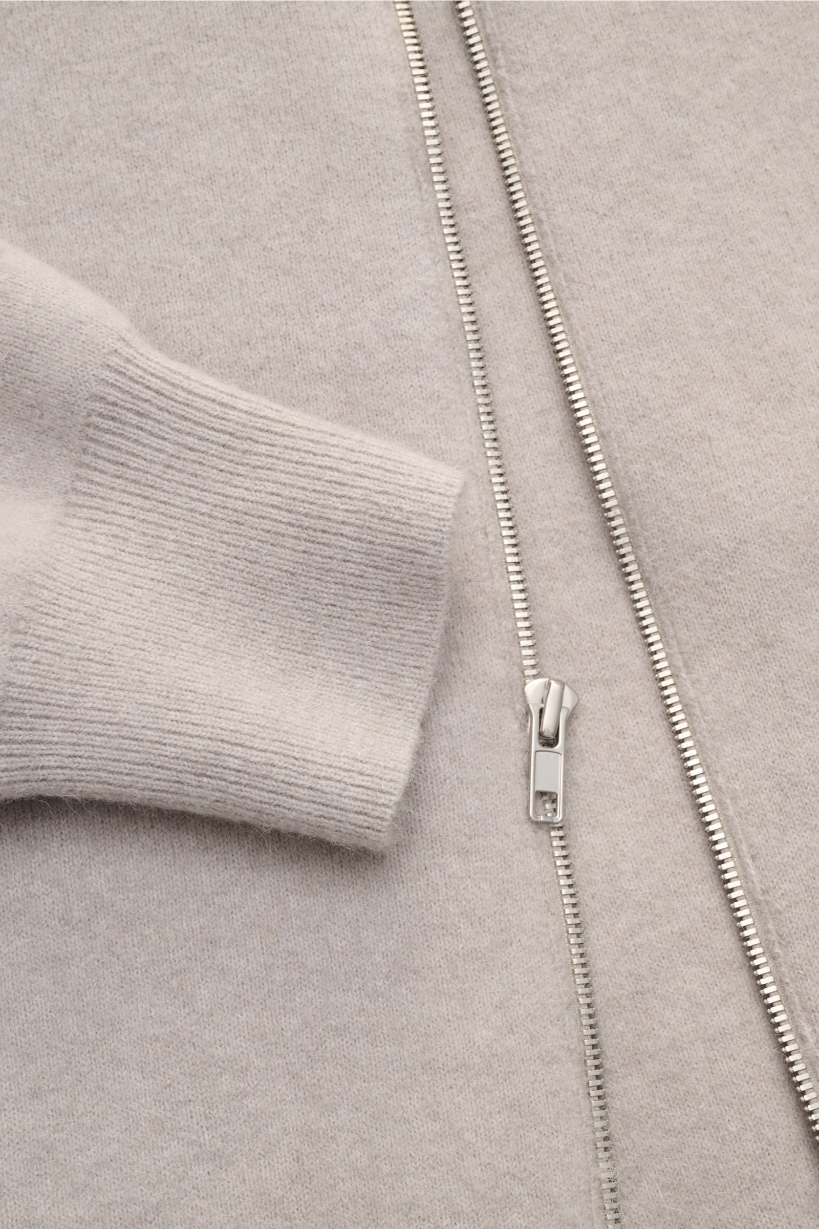 Close-up front view of the Kiefermann Strickjacke 'Fabions' hellgrau meliert cardigan, showing light gray mixed wool fabric, fine knit texture, silver zipper, and ribbed cuff. Luxuriöses Basic für die kalte Jahreszeit: Die Strickjacke im Blouson-Stil von 