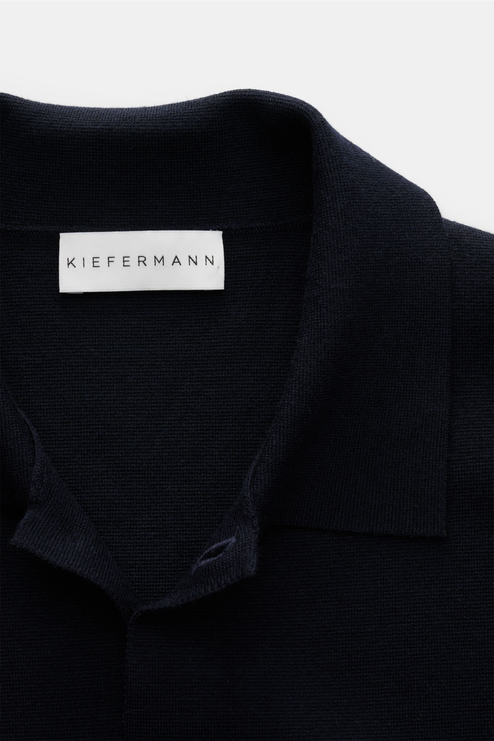 Close-up top-front view of the dark Kiefermann Merino Jersey-Cardigan 'Clemenso' hellgrau collar and label, showcasing fine merino wool texture. Für Momente, in denen Schlichtheit zur stärksten Form von Stil wird: Der Cardigan 'Clemenso' von KIEFERMANN