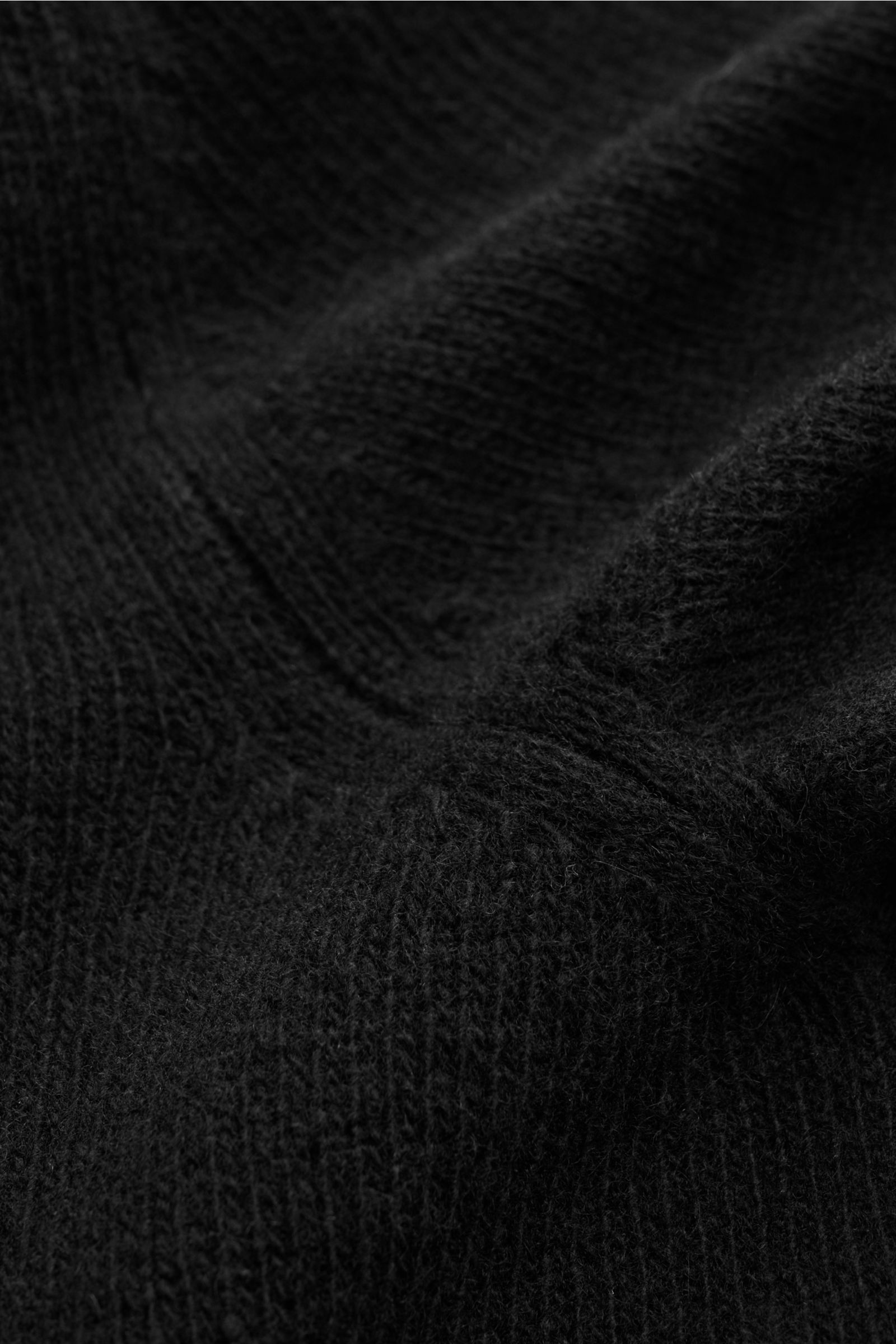 Close-up view of the soft, mid-fine knit texture of the Moorer Cardigan 'Allyn' schwarz, made from wool and cashmere with ribbed cuffs. So fühlt sich Luxus an: Der Cardigan 'Allyn' kombiniert edlen Strick aus Wolle und Cashmere mit smarten Details wie den