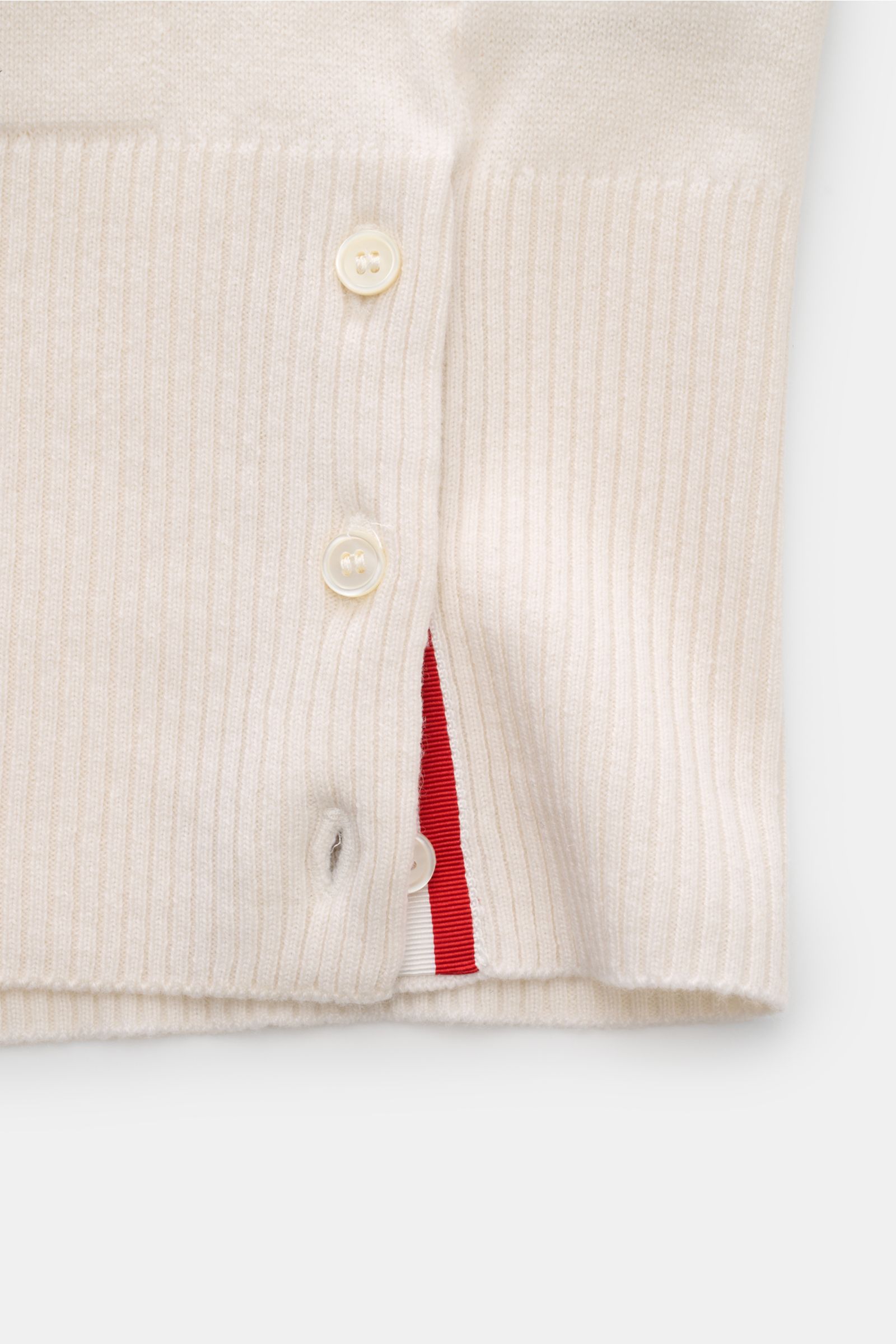 Close-up side view of the Thom Browne Cashmere Cardigan offwhite showing ribbed knit, button placket, side slit with buttons, and red-white trim, made of pure cashmere with a soft touch and regular fit. Vielseitiger Style-Favorit: Der Cashmere Cardigan vo