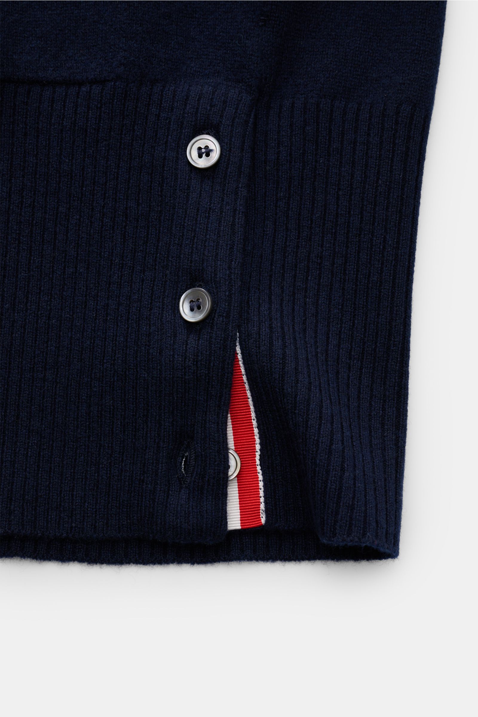 Close-up side view of Thom Browne Cashmere Cardigan navy showing ribbed knit, buttoned side slit with red and white trim, and texture details.