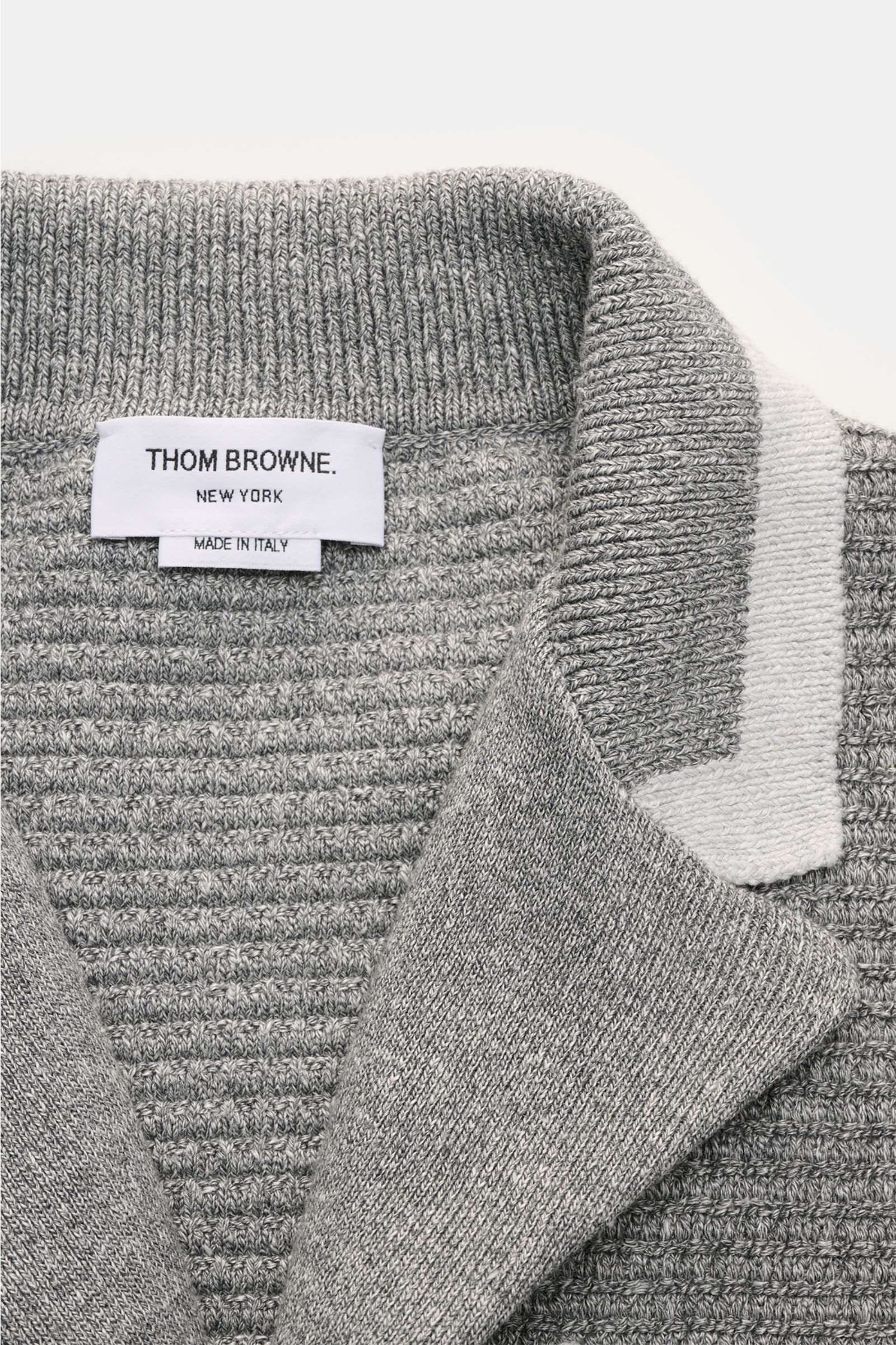 Nahaufnahme von Thom Browne Cardigan hellgrau meliert mit Revers-Ausschnitt, markantem Strickmuster, Tricolore-Ripsband und hochwertigem Leinen-Baumwoll-Mix.