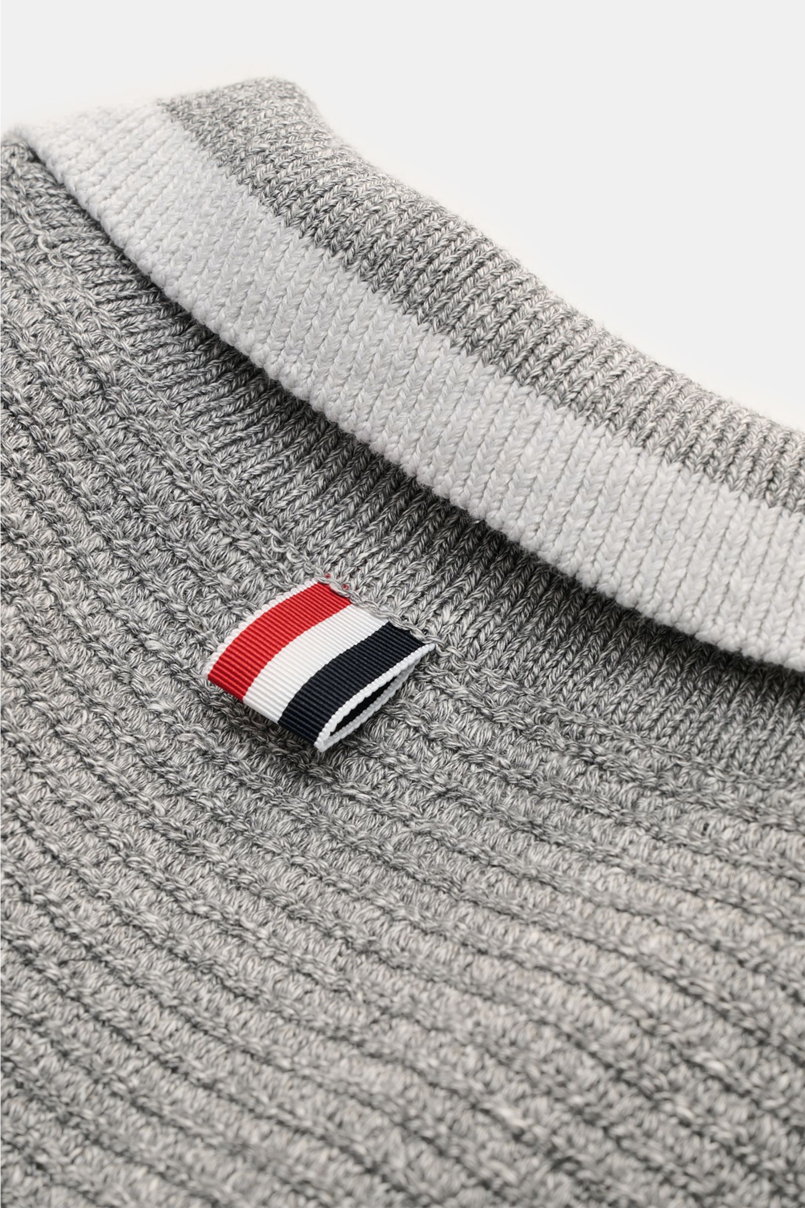 Nahaufnahme des Thom Browne Cardigan hellgrau meliert von hinten oben, zeigt das markante Strickmuster, Ripsband in Tricolore am Kragen und Weblabel.