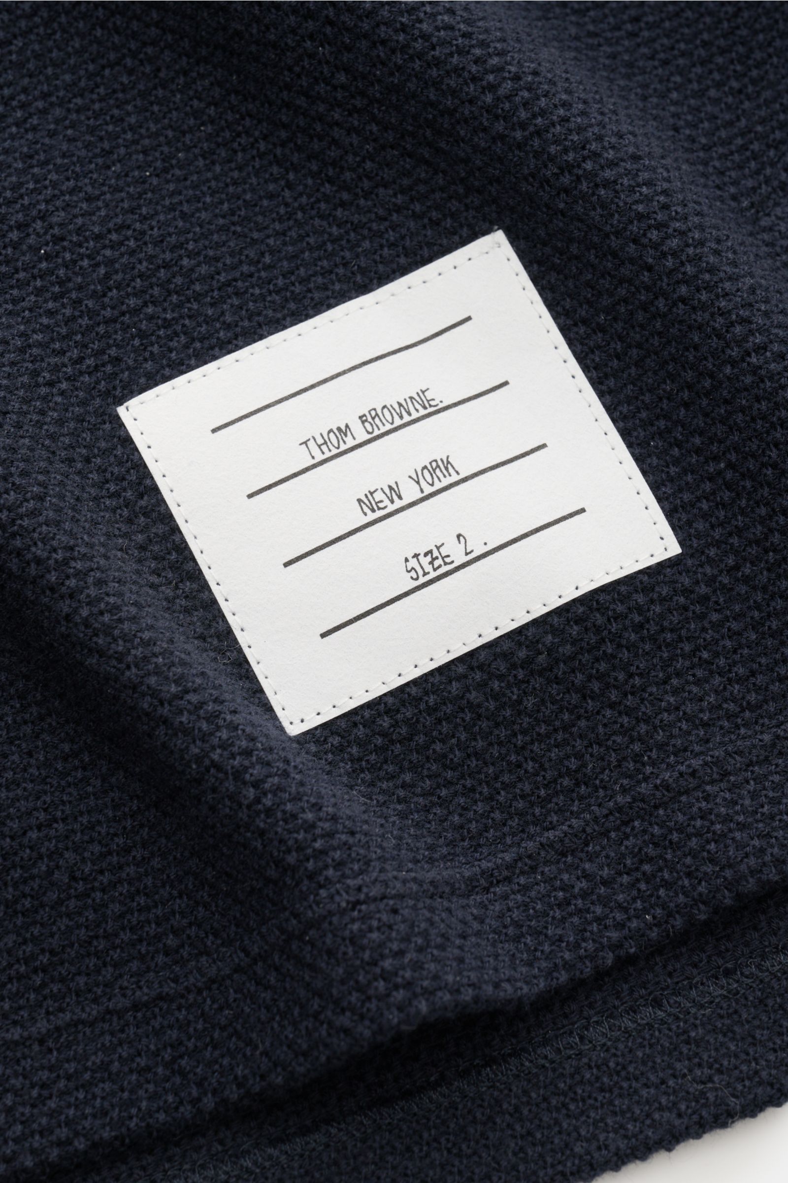 Close-up front view of the Thom Browne Cardigan navy showing finely textured pure cotton knit and white woven label with brand details.