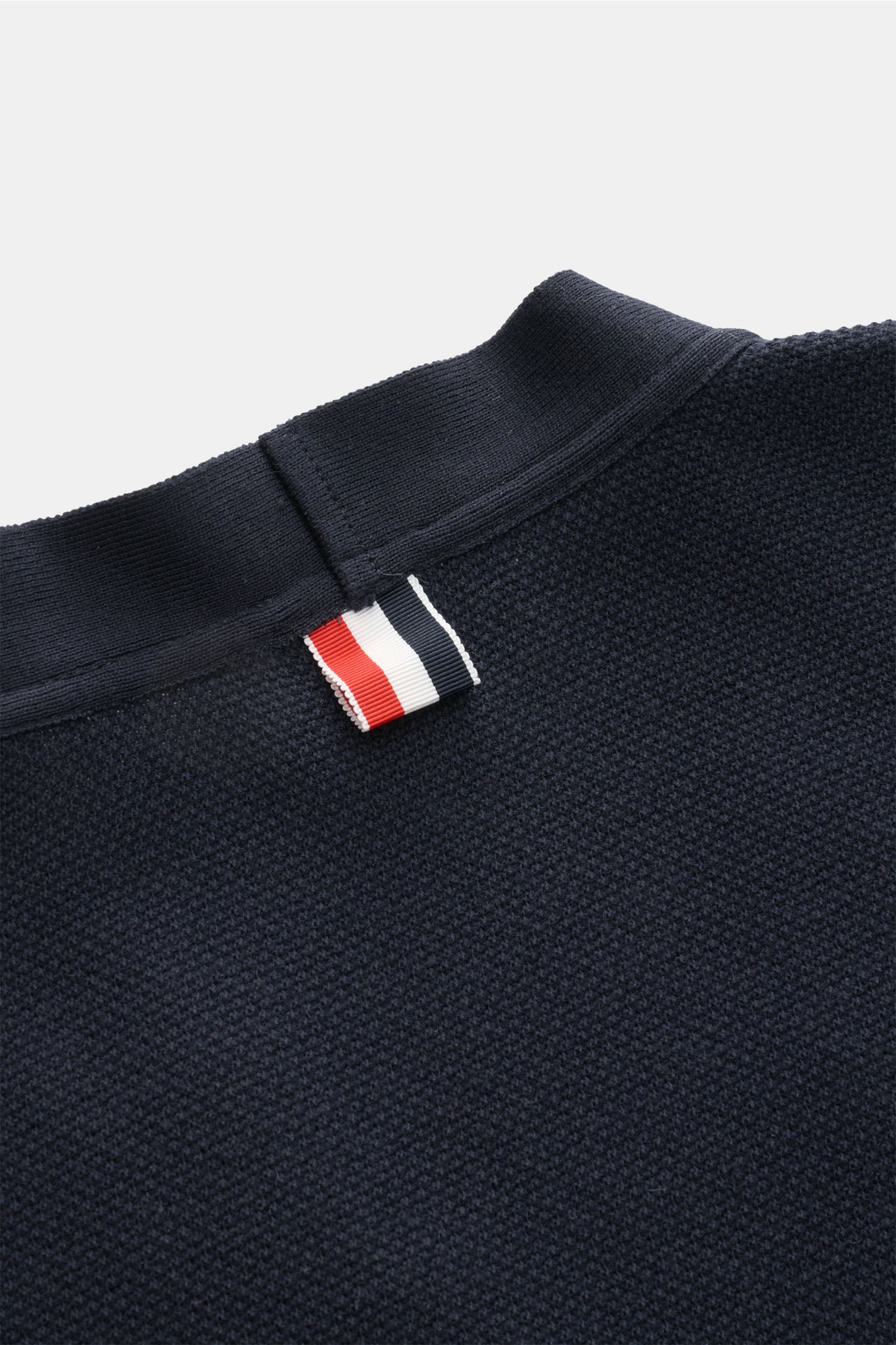 Close-up rear view of Thom Browne Cardigan navy showing pure cotton finely textured knit fabric with signature tricolour woven label under ribbed collar.