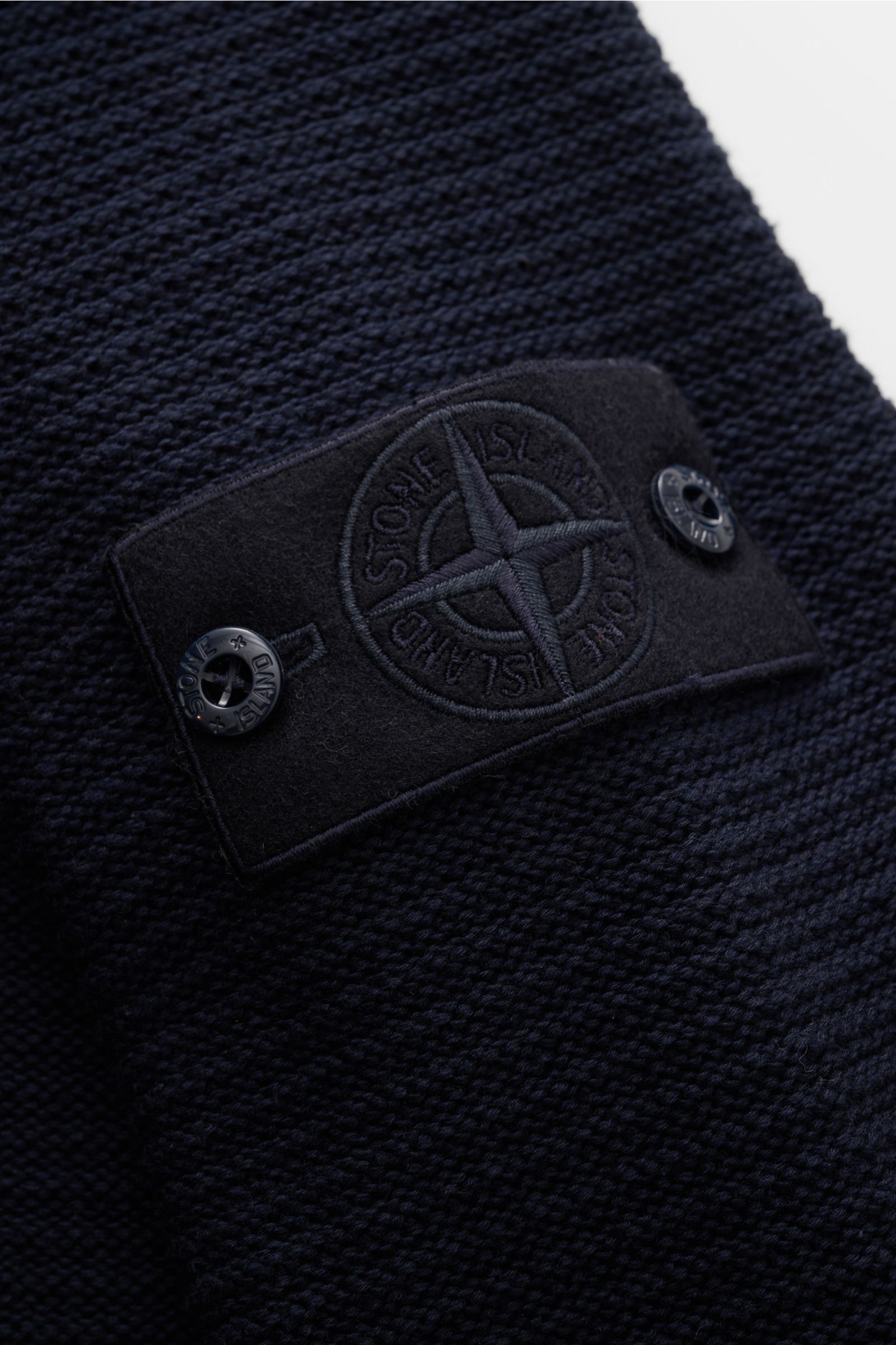 Stone Island Strickjacke 'Ghost Piece' navy im Nahaufnahmefoto des tonalen Badges am Oberarm, mittelfeines Strickbild, weicher Griff.