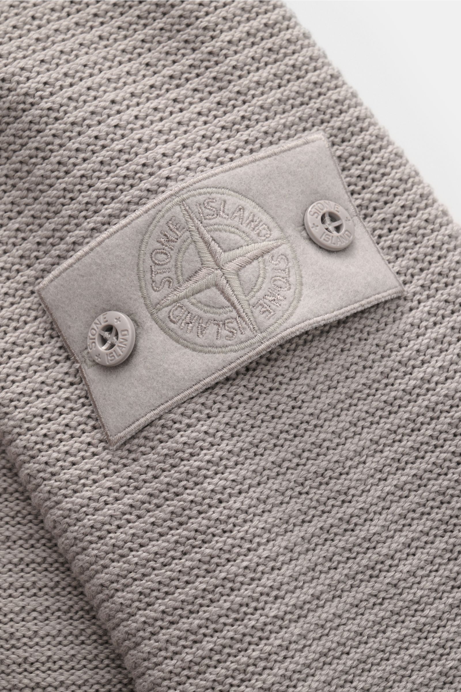 Nahaufnahme der tonalen Stone Island Strickjacke 'Ghost Piece' grau mit mittelfeinem Strickbild und Badge am Oberarm.