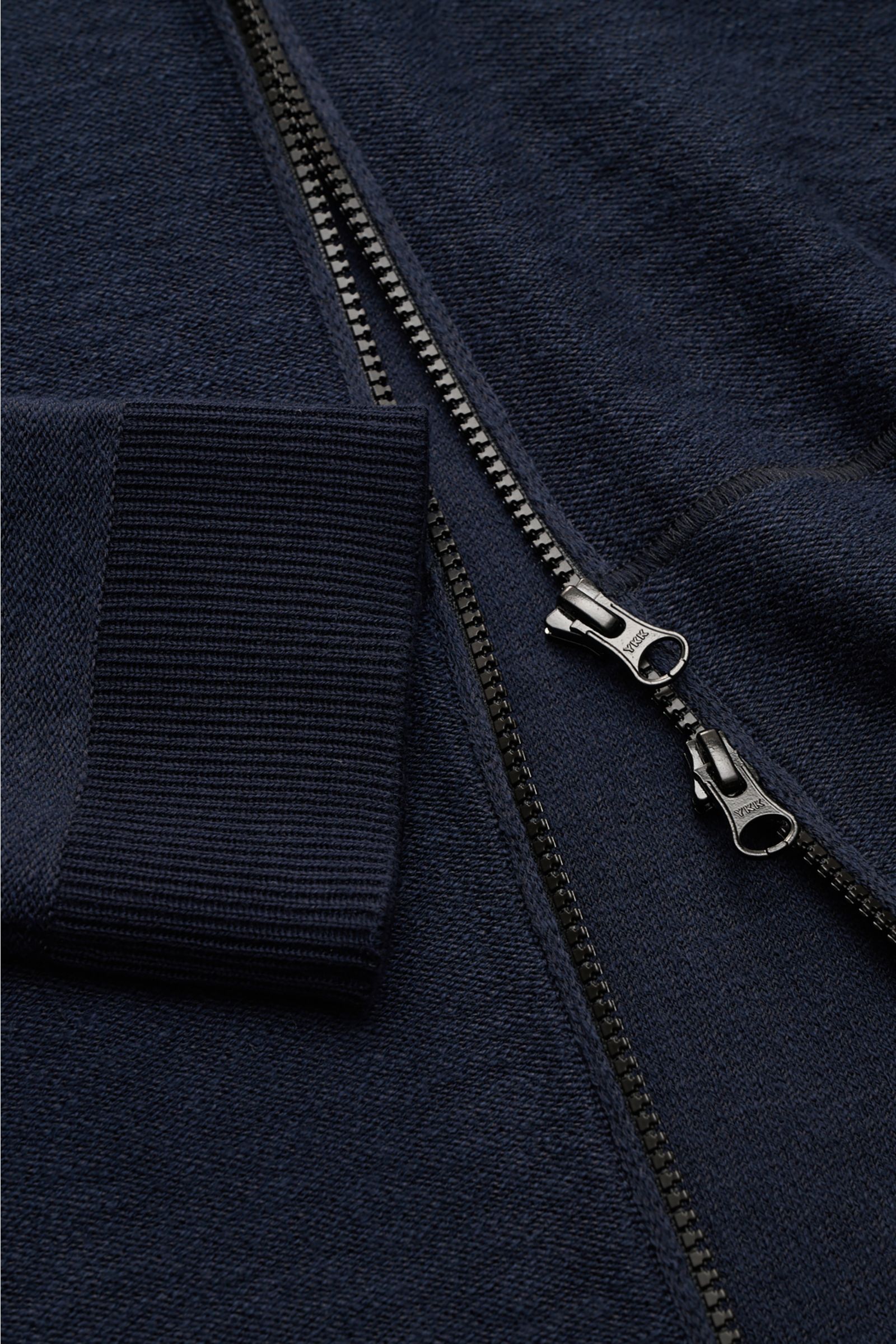 Stone Island Sweatjacke navy in Nahaufnahme von oben, links gestrickt mit Kapuze, Reißverschluss, Rippbündchen und markentypischem Badge.