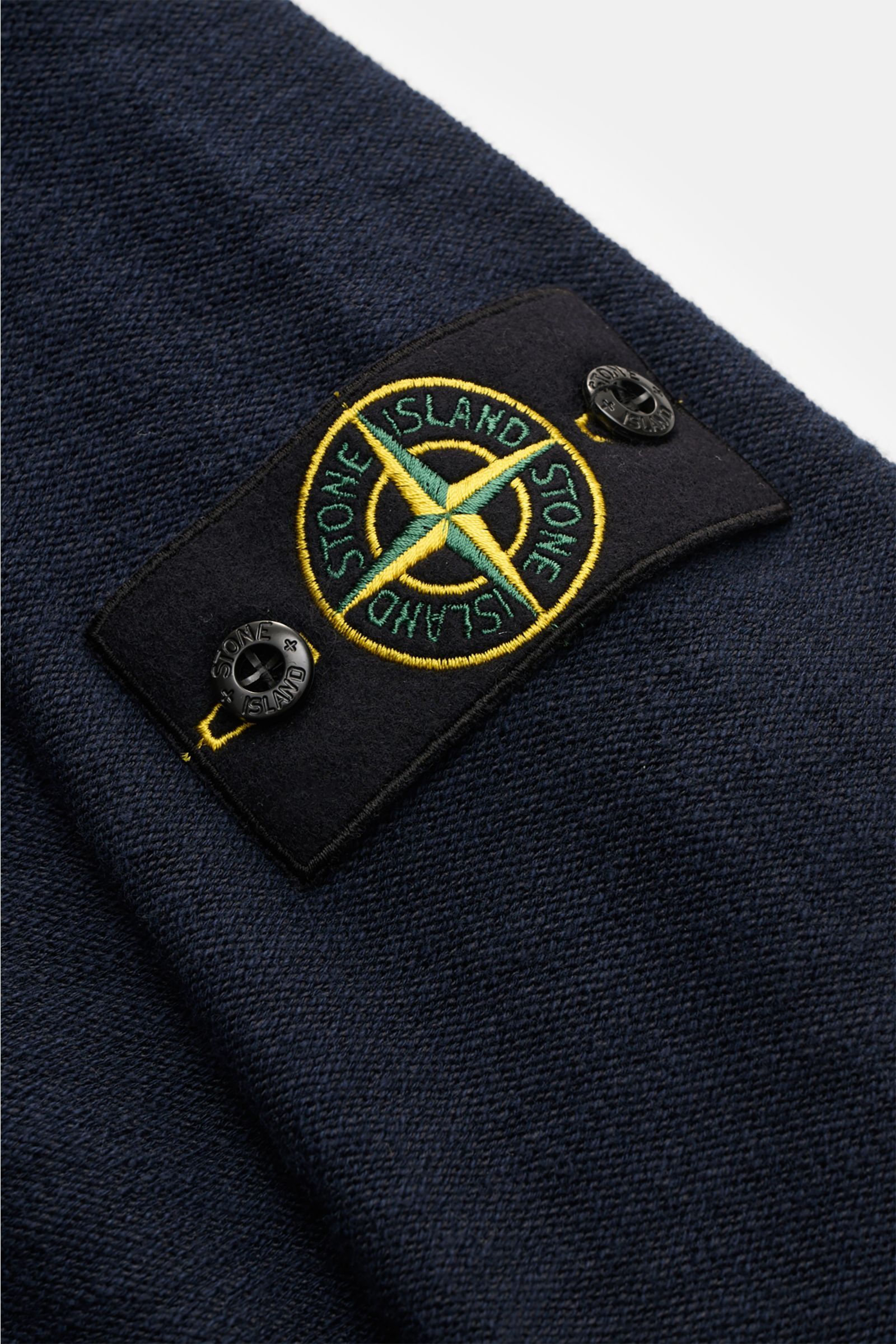 Stone Island Sweatjacke navy im Nahaufnahmefoto, linksgestrickte Struktur, markentypisches Kompass-Badge am Ärmel aus Baumwoll-Microfaser-Mix.