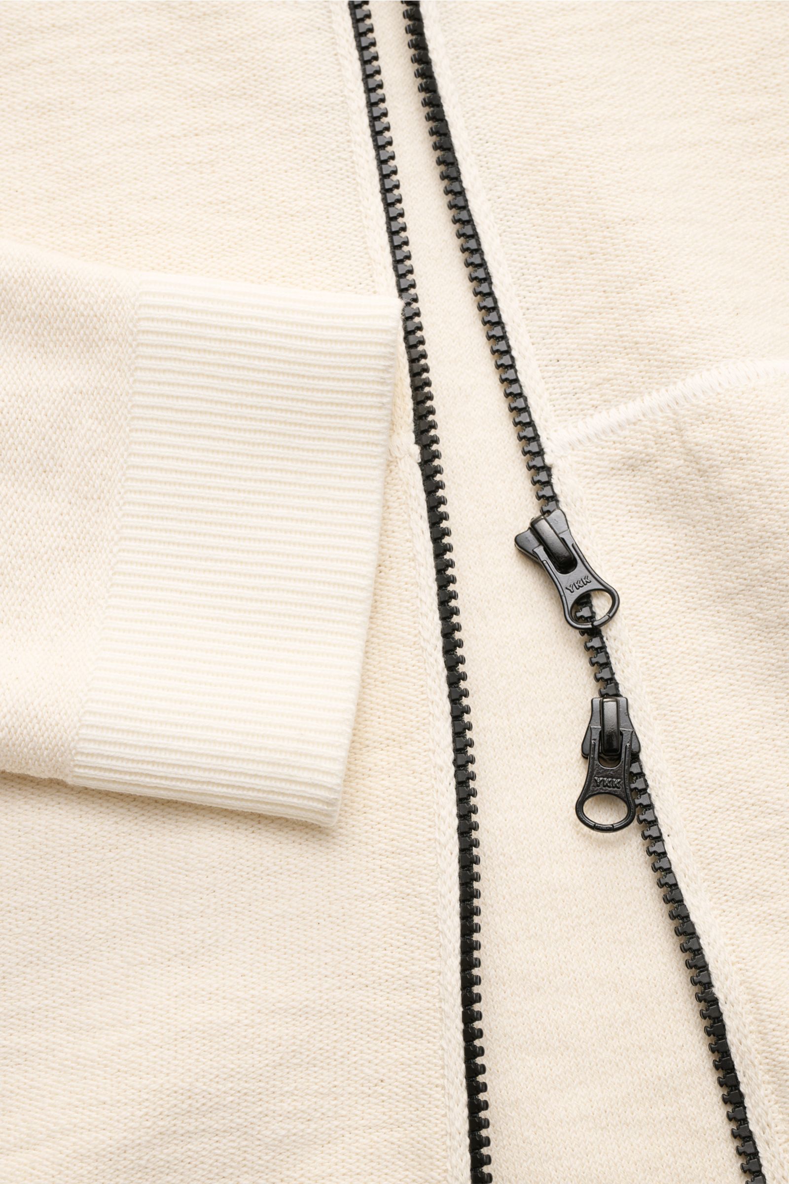 Stone Island Sweatjacke creme shown in a close-up front view featuring a black double zipper, ribbed cuff, and textured cream knit fabric. Strick mit Twist: Die sportive Jacke mit Kapuze im modernen Linksstrick von STONE ISLAND wird zum idealen Freizei