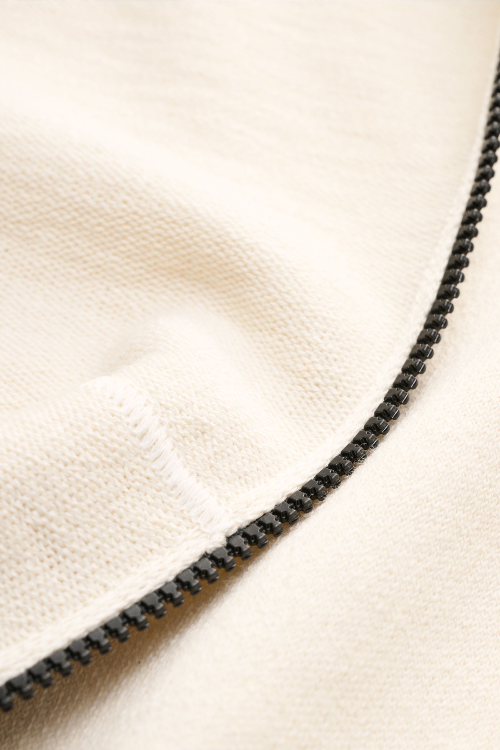 Close-up view of the cream-colored Stone Island Sweatjacke creme zipper and knit texture showing regular fit cotton-microfiber blend, left-knit structure, ribbed cuffs, split kangaroo pocket, hood, and signature compass badge on the sleeve. Strick mit 