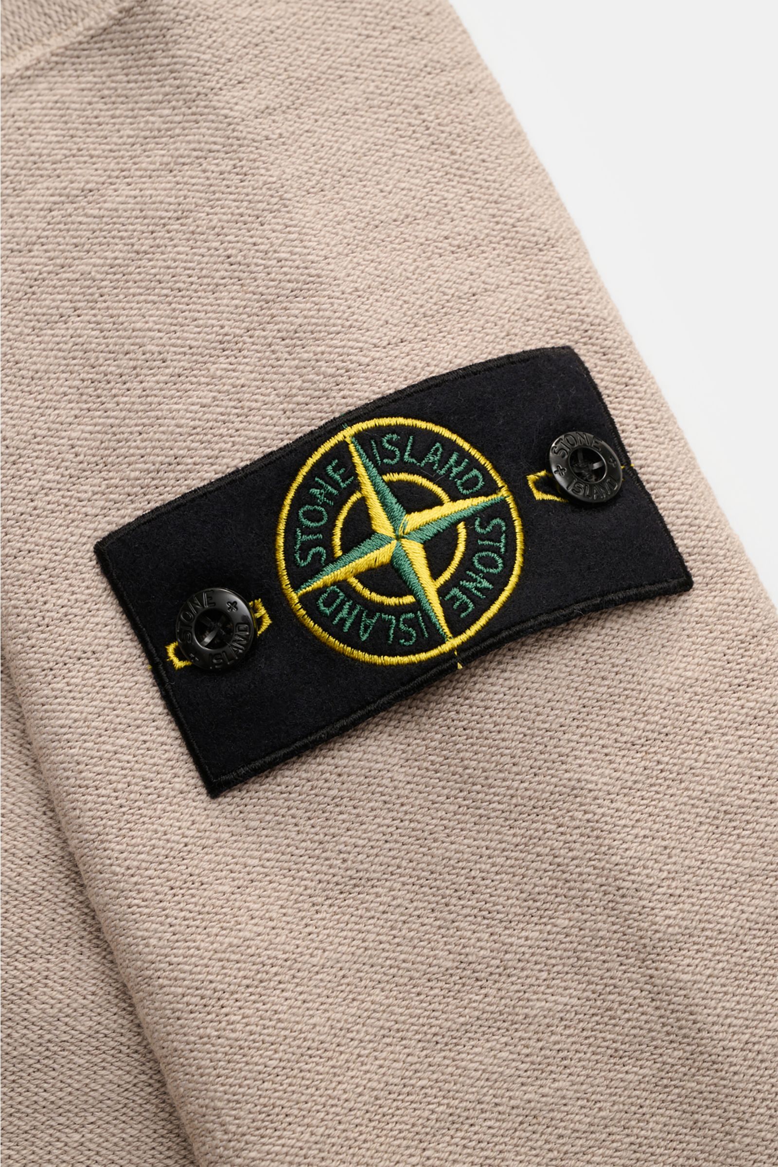 Stone Island Sweatjacke beige, Detailaufnahme von links, linksstrickte Baumwoll-Microfaser mit Kompass-Badge am Ärmel.