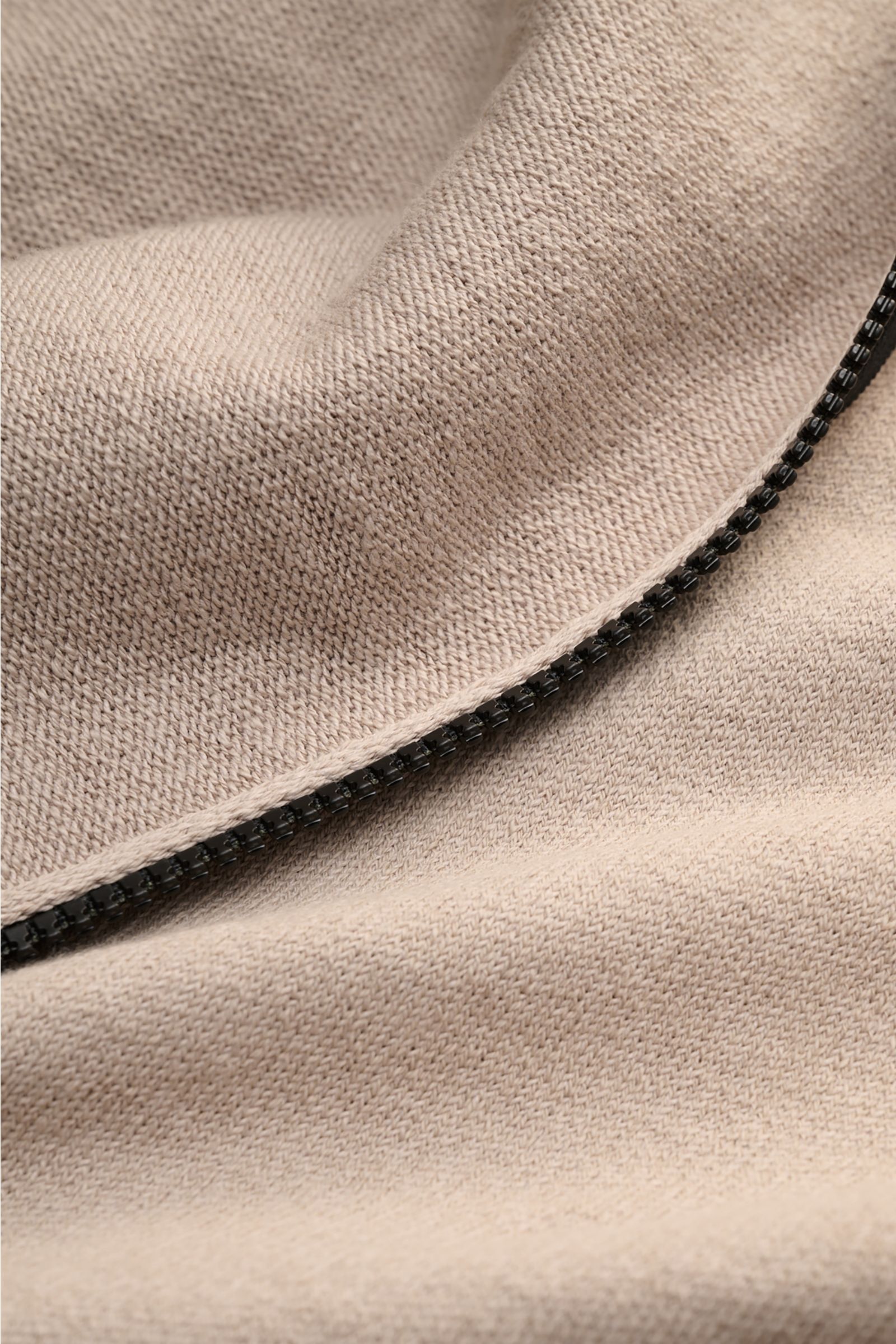 Stone Island Sweatjacke beige in Nahaufnahme, links gestrickter Strickstoff mit leicht griffiger Haptik und Reißverschluss.