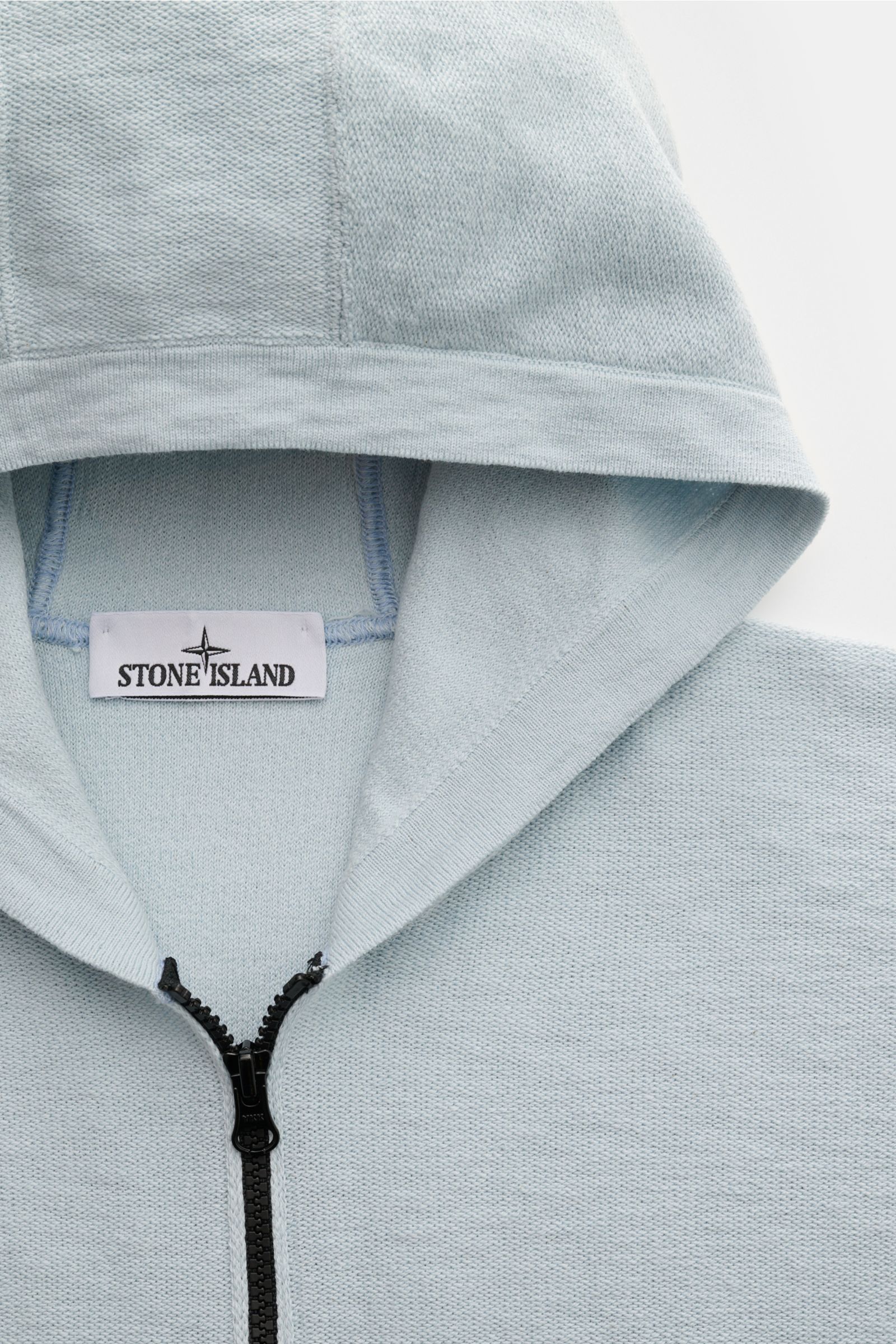 Close-up front view of Stone Island Sweatjacke pastellblau hoodie with zipper, regular fit, cotton-microfiber mix, left-knit texture, ribbed cuffs, and brand compass badge.

Description to include: 
Strick mit Twist: Die sportive Jacke mit Kapuze im moder