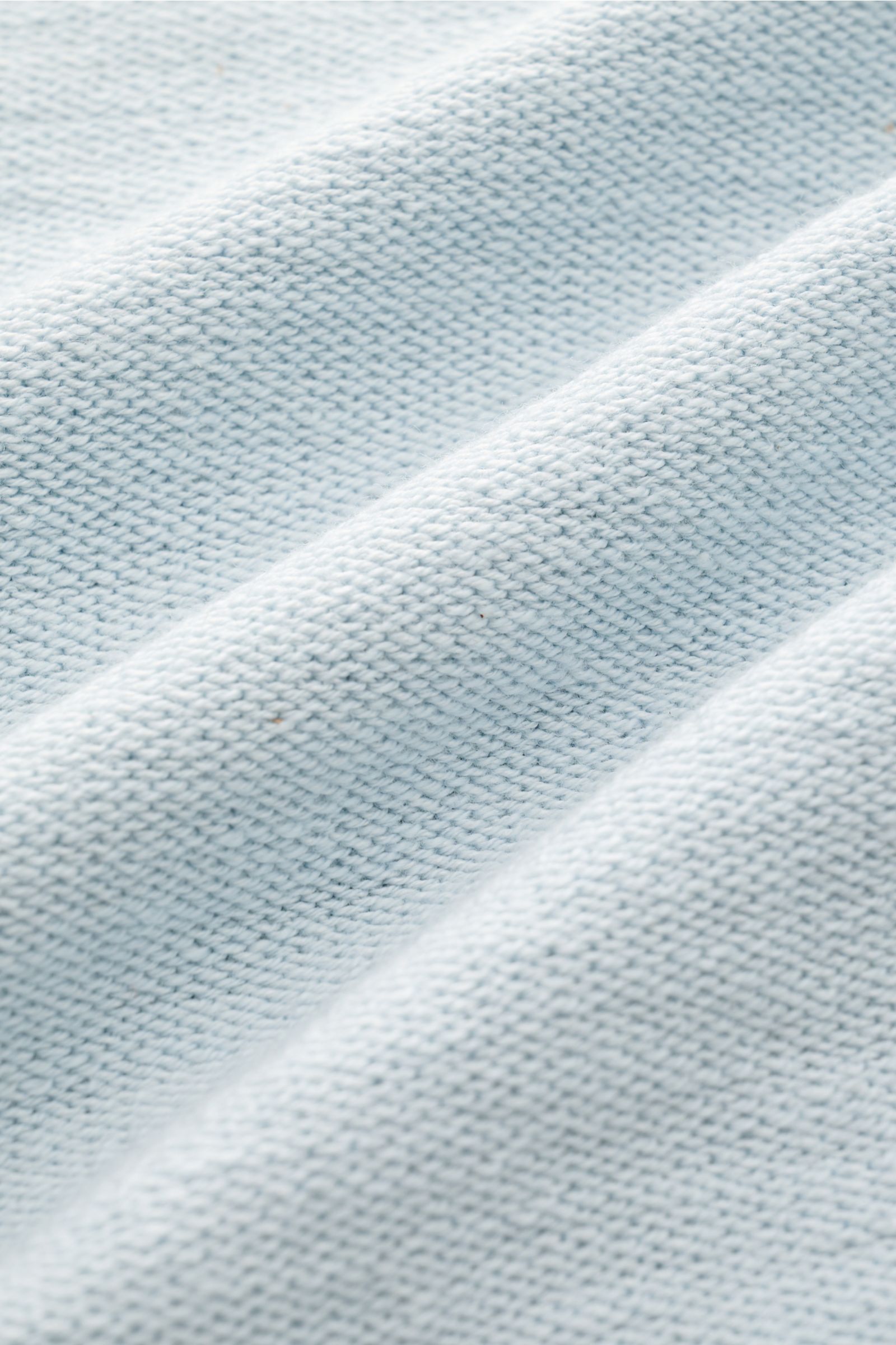 Close-up of the fabric texture of the Stone Island Sweatjacke pastellblau, showing the modern linksstrick knit in pastel blue from a top-down perspective.

Description: Strick mit Twist: Die sportive Jacke mit Kapuze im modernen Linksstrick von STONE I
