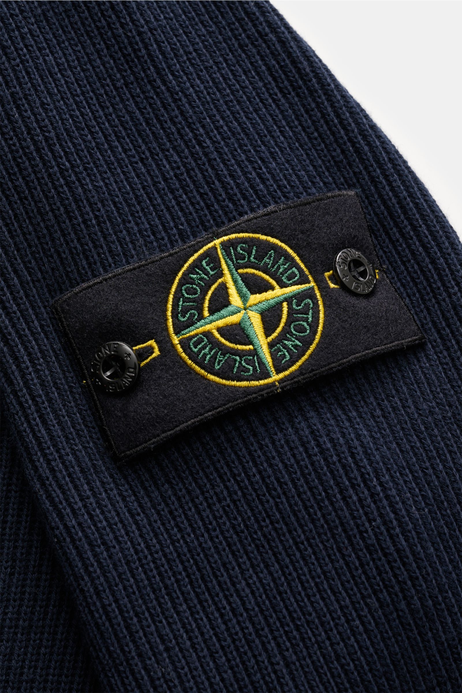 Nahaufnahme der Stone Island Strickjacke 'Rib' navy im klassischen Rippstrick-Design mit Kompass-Badge am Ärmel aus reiner Baumwolle.