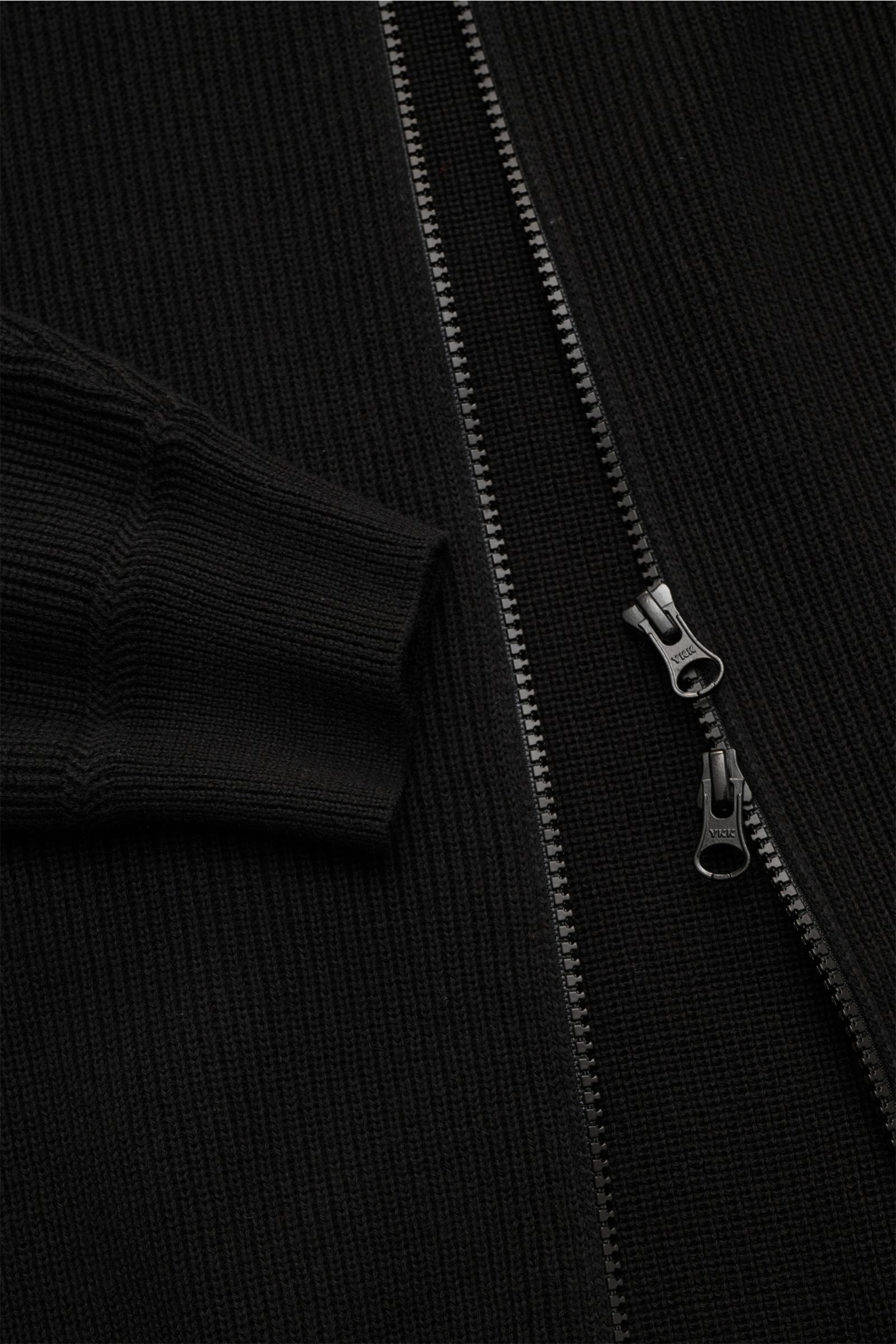 Close-up front view of the Stone Island Strickjacke 'Rib' schwarz, showing ribbed knit cotton, two-way zipper, soft cuffs. Zeitloses Layering-Piece: Die Strickjacke von STONE ISLAND wird mit ihrem Rippstrick-Design aus reiner Baumwolle zum vielseitigen