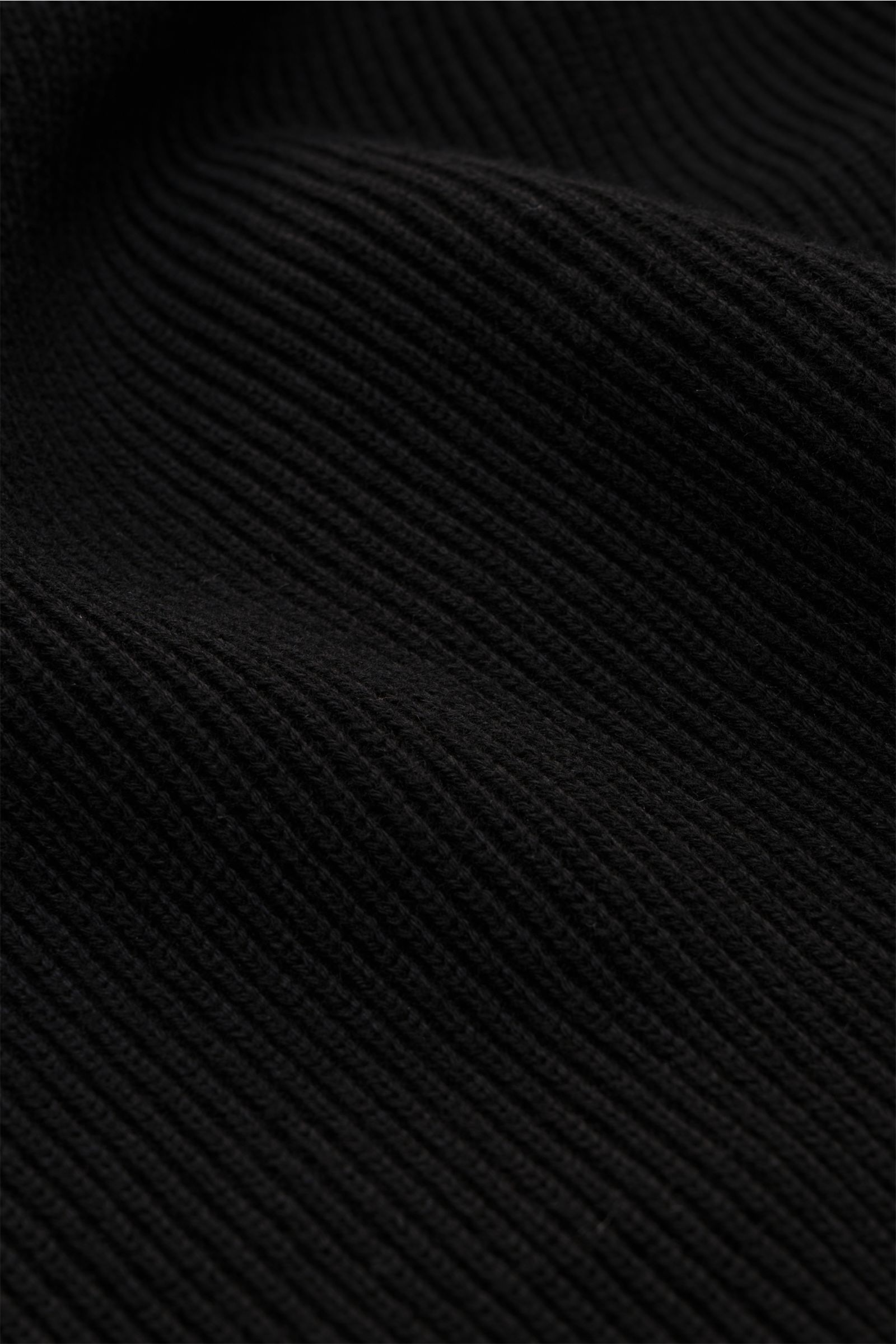 Close-up front view of Stone Island Strickjacke 'Rib' schwarz showing black ribbed knit texture made of pure cotton with soft feel and medium-fine knit pattern. Zeitloses Layering-Piece: Die Strickjacke von STONE ISLAND wird mit ihrem Rippstrick-Design au