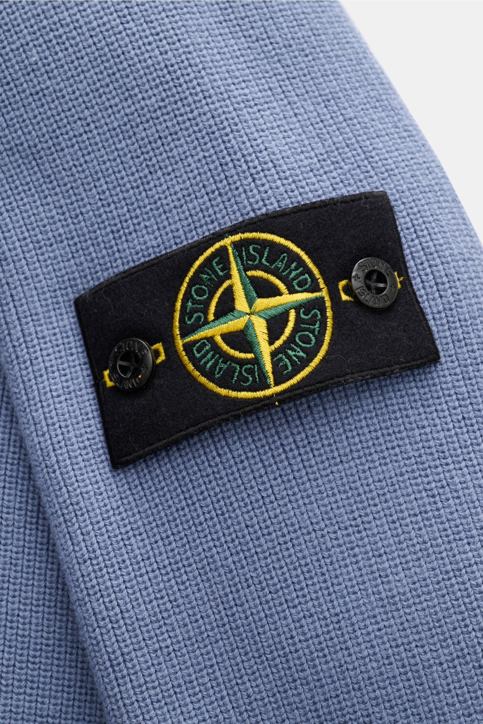 Stone Island Cardigan rauchblau, Nahaufnahme des feinen Rippstrick-Designs aus reiner Baumwolle mit Kompass-Badge am Ärmel.