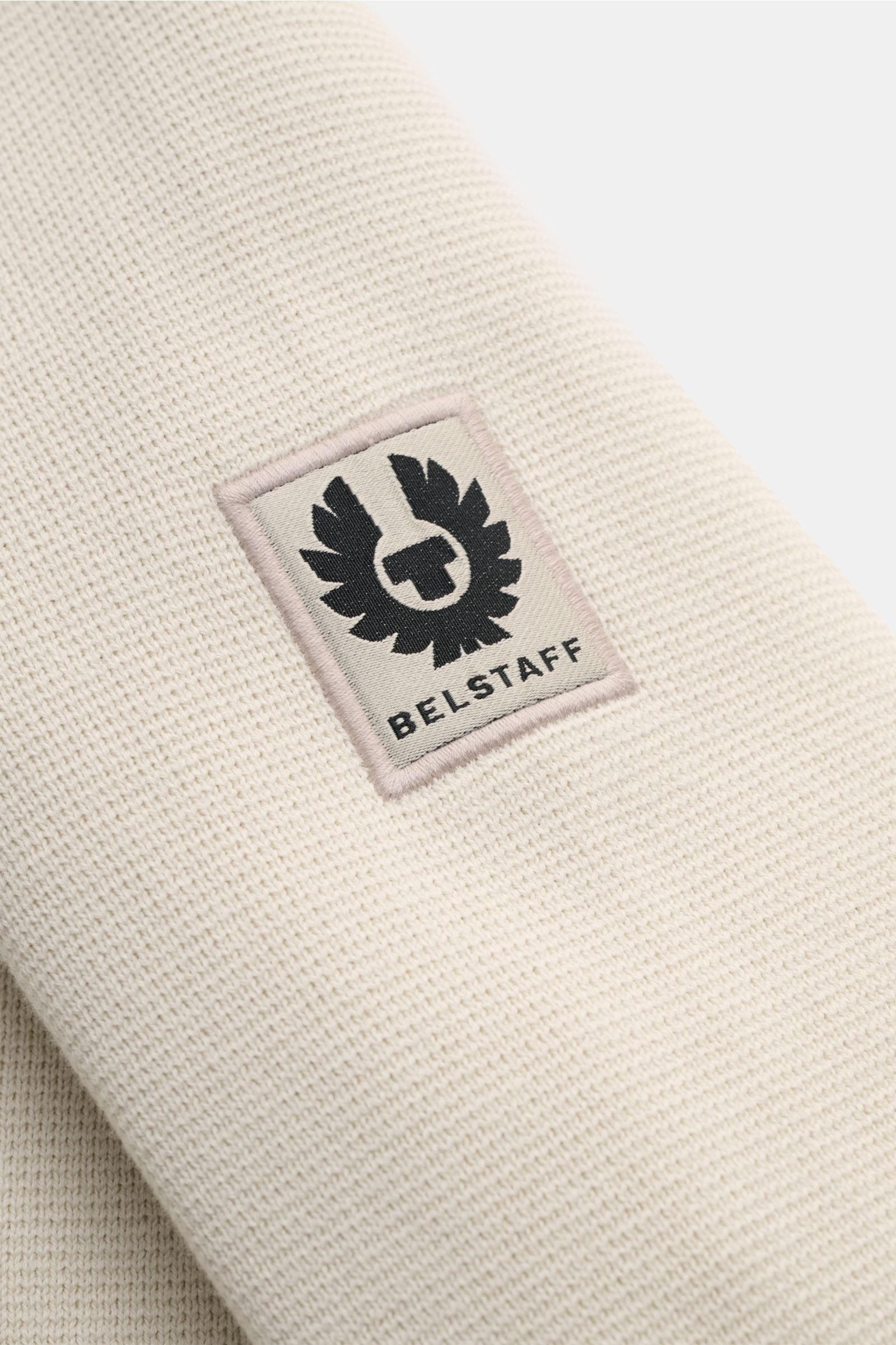 Belstaff Strickjacke 'Verge' creme in Nahaufnahme von oben, feines Strickbild, Baumwolle, Schulterdetails, Weblabel am Ärmel.